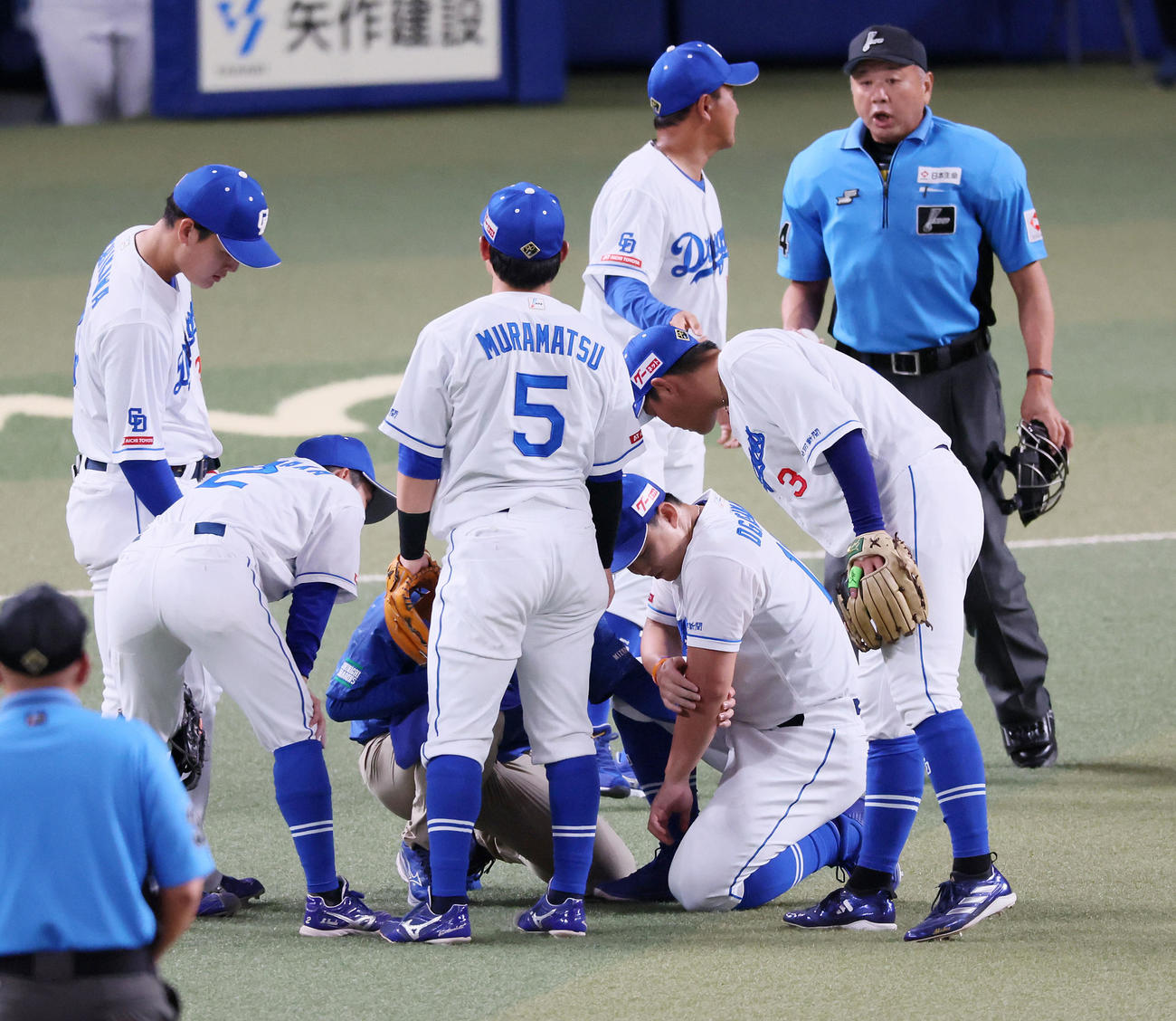 中日対阪神　1回表阪神無死、小笠原は近本の打球を受けてグラウンドにひざまづき左腕をトレーナーに触られる（撮影・加藤哉）