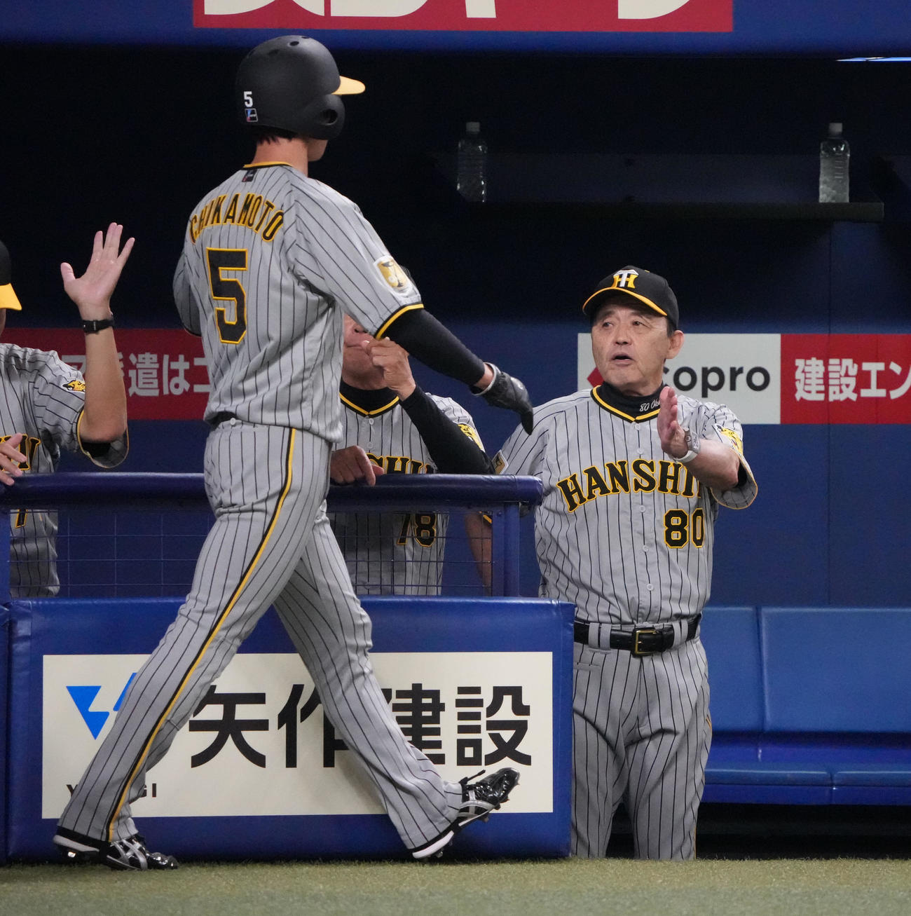 中日対阪神　1回表阪神1死一、二塁、佐藤輝の右前適時打で生還した近本を迎える岡田監督（右）（撮影・森本幸一）