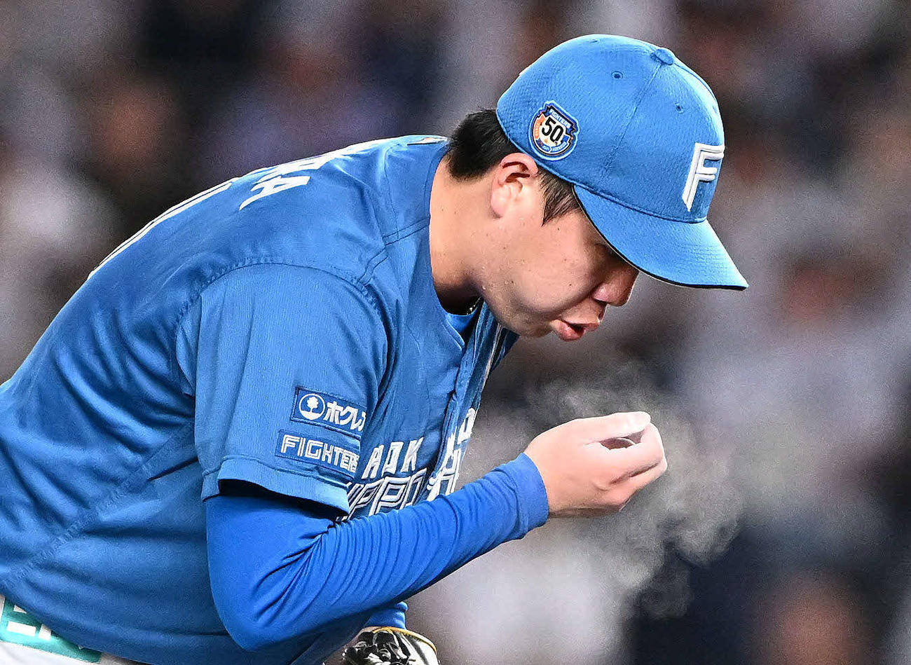 ロッテ対日本ハム　ロジンの粉を吹く日本ハム先発の金村（撮影・滝沢徹郎）
