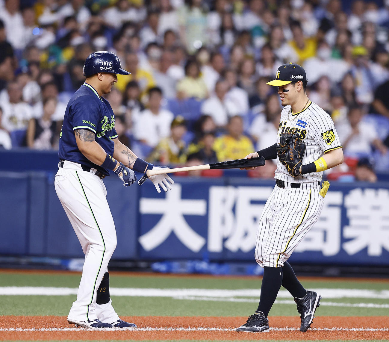 阪神対ヤクルト　6回表ヤクルト1死三塁、オスナ（左）がファウルを放った際に飛ばしたバットを直接手渡す佐藤輝（撮影・藤尾明華）