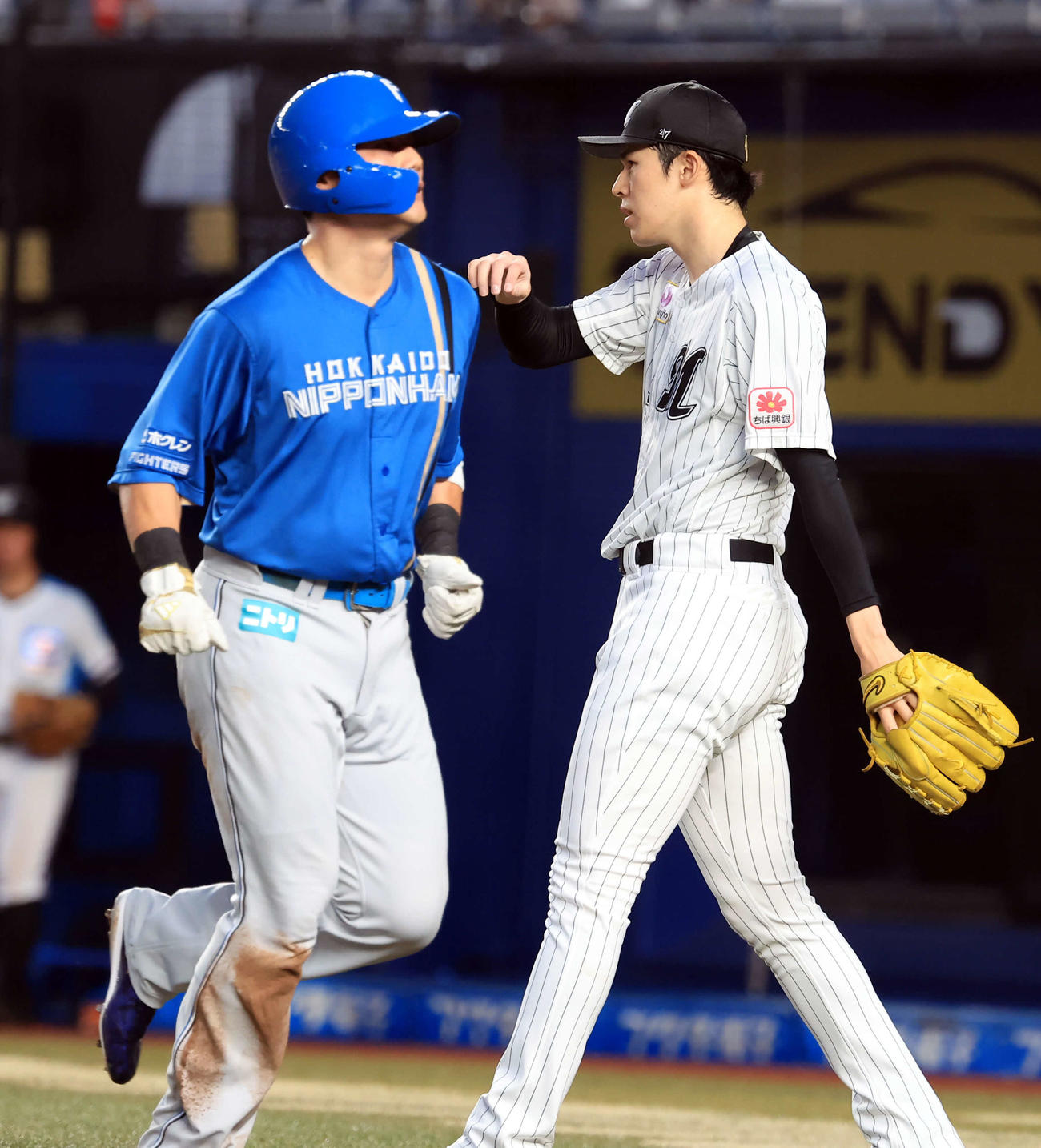 ロッテ対日本ハム　2回表日本ハム無死二塁、レイエスの右適時打で生還した清宮（左）の奥で汗をぬぐう佐々木（撮影・浅見桂子）