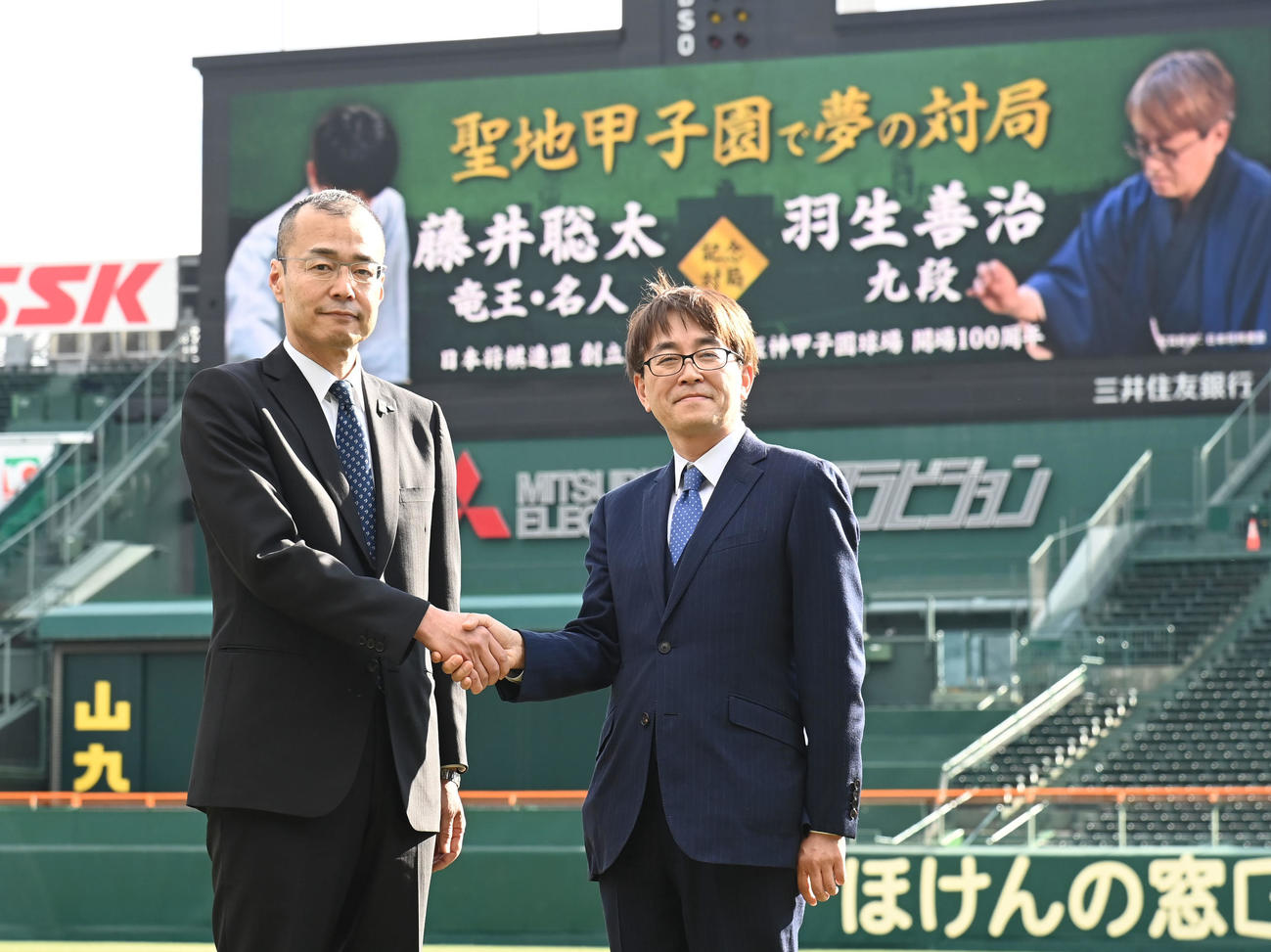 2024年1月、甲子園球場で握手をする（左から）阪神甲子園球場長・向井格郎、日本将棋連盟会長・羽生善治