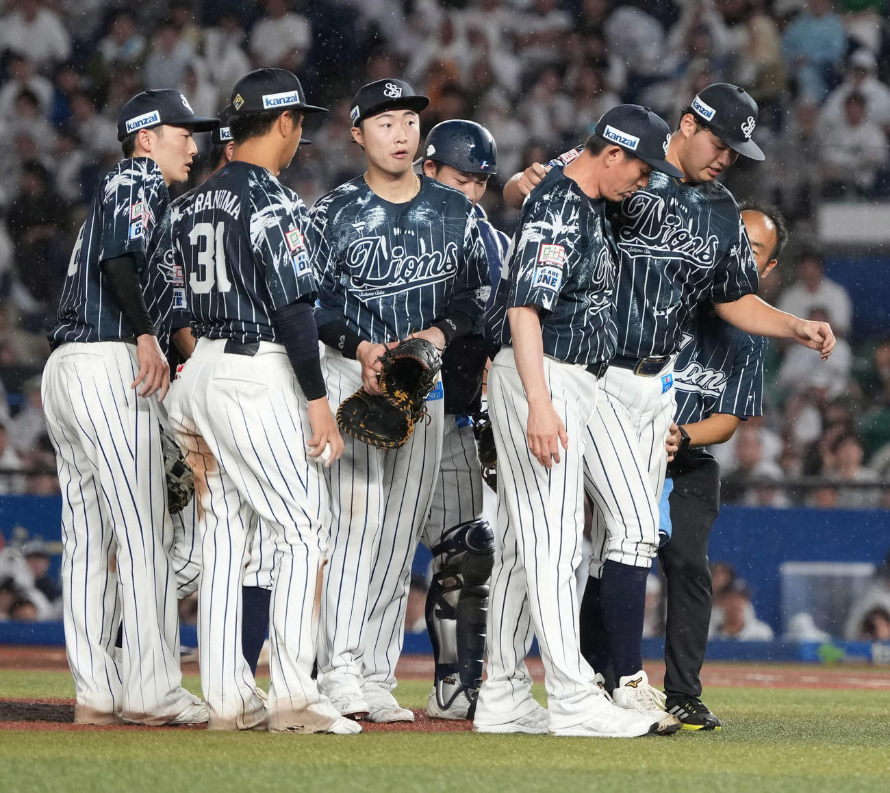 ロッテ対西武　7回裏ロッテ2死二塁、ソトの打球が直撃した西武先発の渡辺（右）は豊田投手コーチの肩を借りながら治療のためベンチへ引き揚げる（撮影・小沢裕）