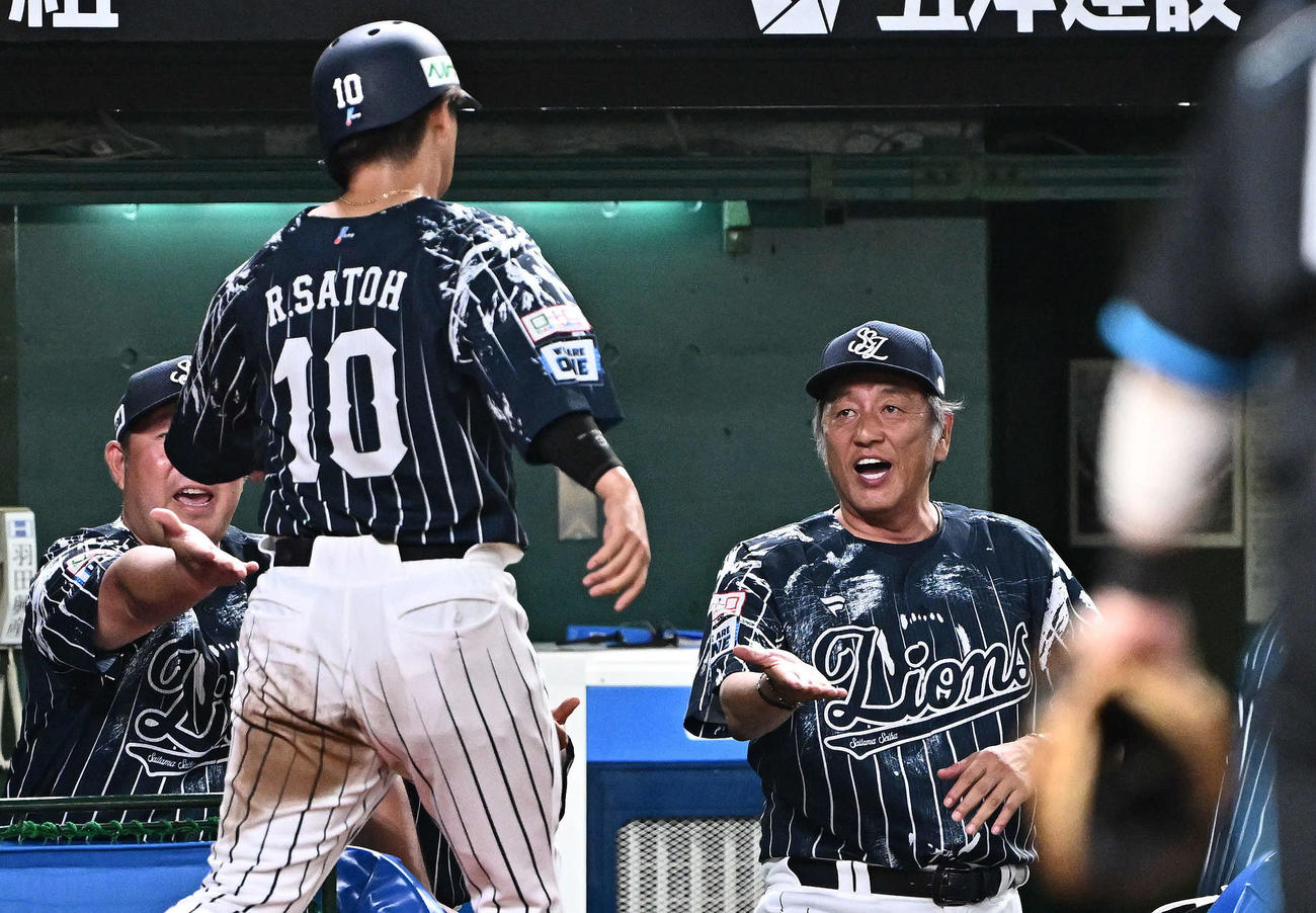 西武対日本ハム　6回裏西武無死一、二塁、敵失から生還した佐藤龍（手前）を迎える渡辺GM兼監督代行（撮影・滝沢徹郎）