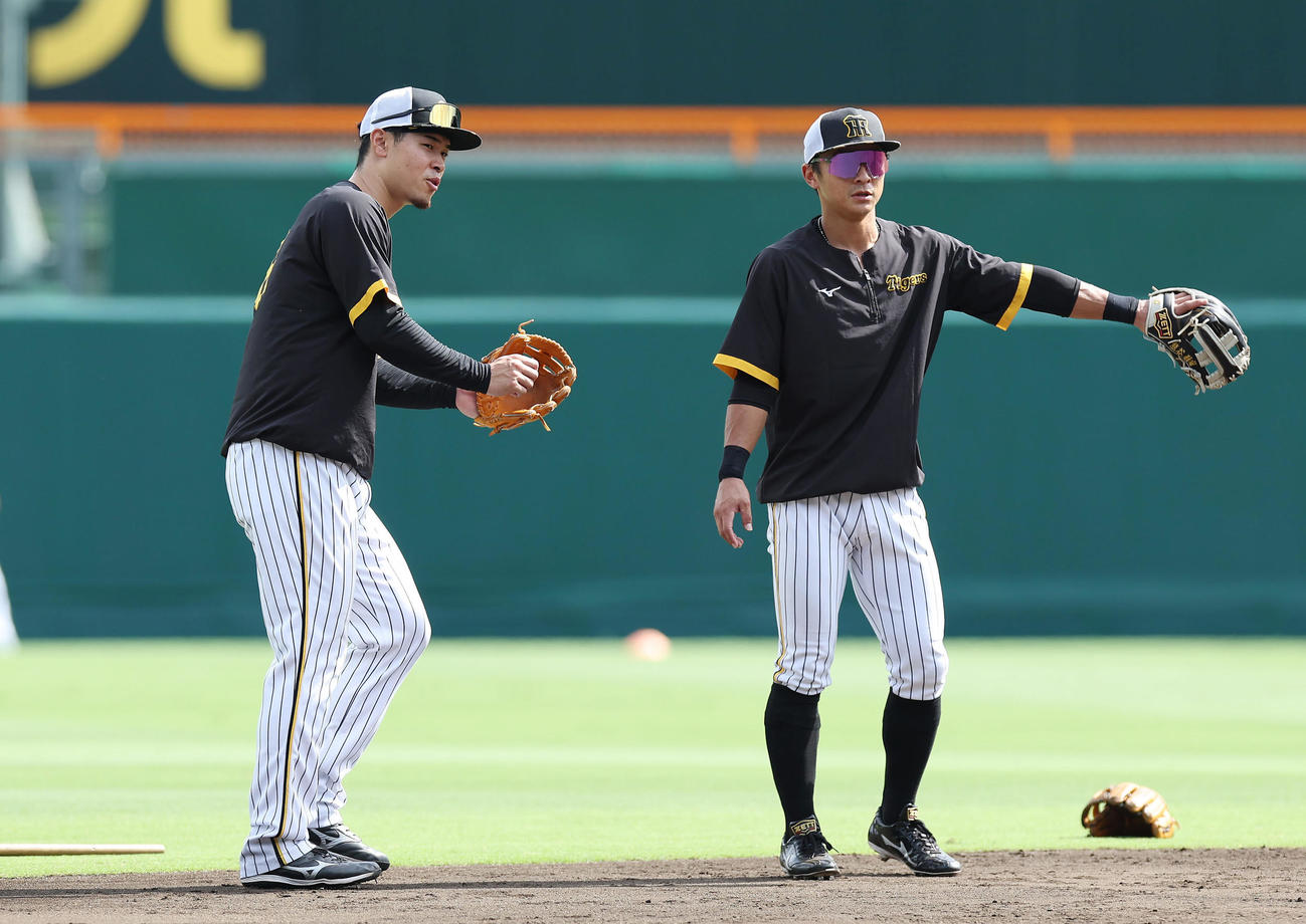 阪神対巨人　ノックを受けた後、阪神熊谷（右）と言葉を交わす佐藤輝（撮影・前田充）