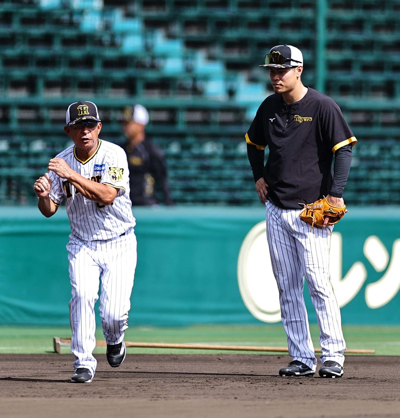 佐藤輝（右）に守備の指導する馬場コーチ（撮影・上田博志）