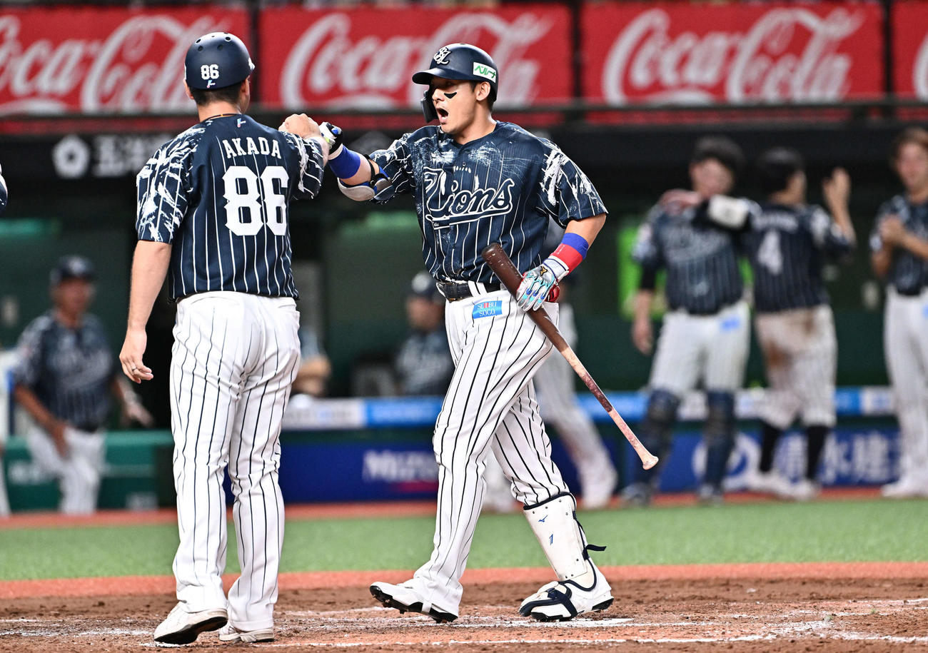 西武対日本ハム　8回裏西武2死三塁、右越え2点本塁打を放った代打栗山（右）は生還し赤田コーチとタッチをかわす（撮影・滝沢徹郎）