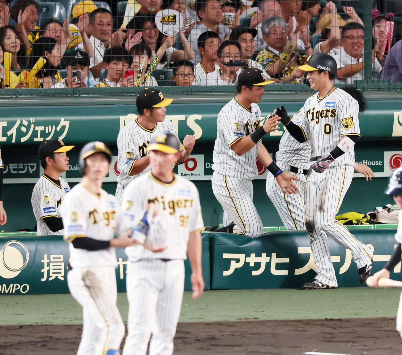 阪神対中日　7回裏阪神1死三塁、近本の右適時打で生還しナインとタッチする三走木浪（右）。左は高橋（撮影・加藤哉）