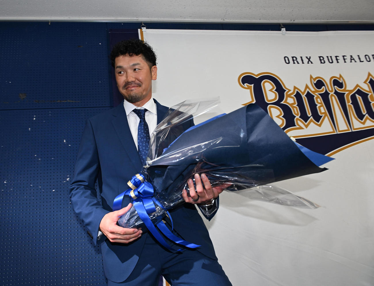 引退会見を行い、花束を手に引き揚げるオリックスTー岡田（撮影・和賀正仁）