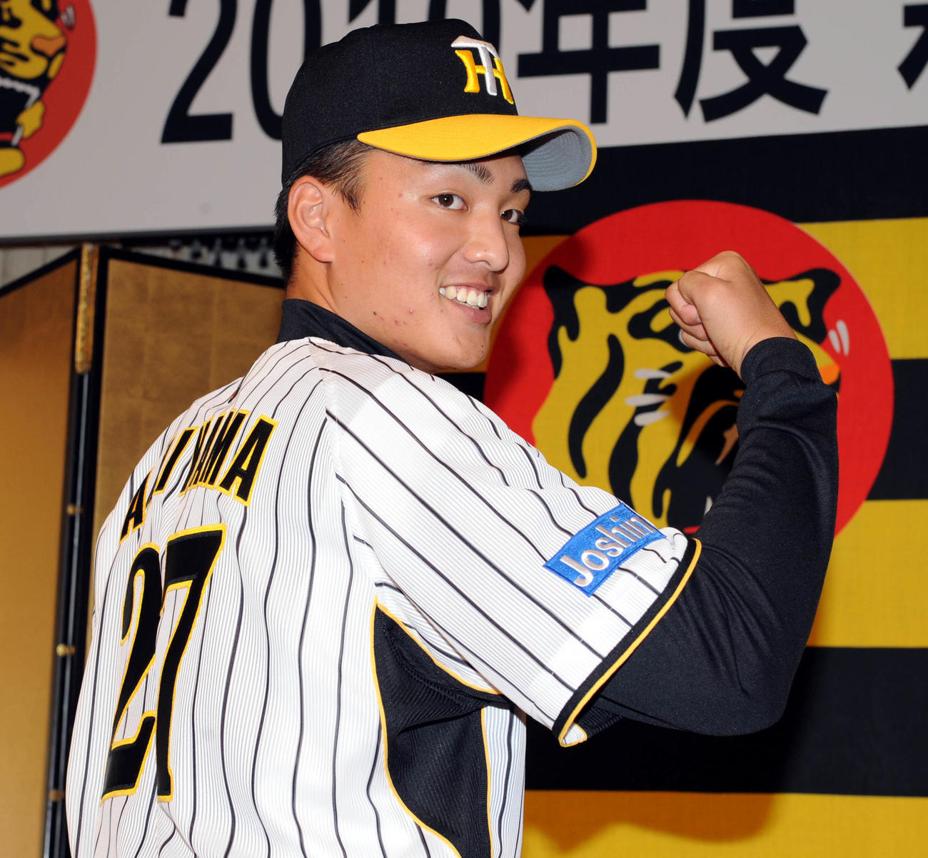09年12月7日、阪神新入団発表会見で秋山は笑顔でポーズ