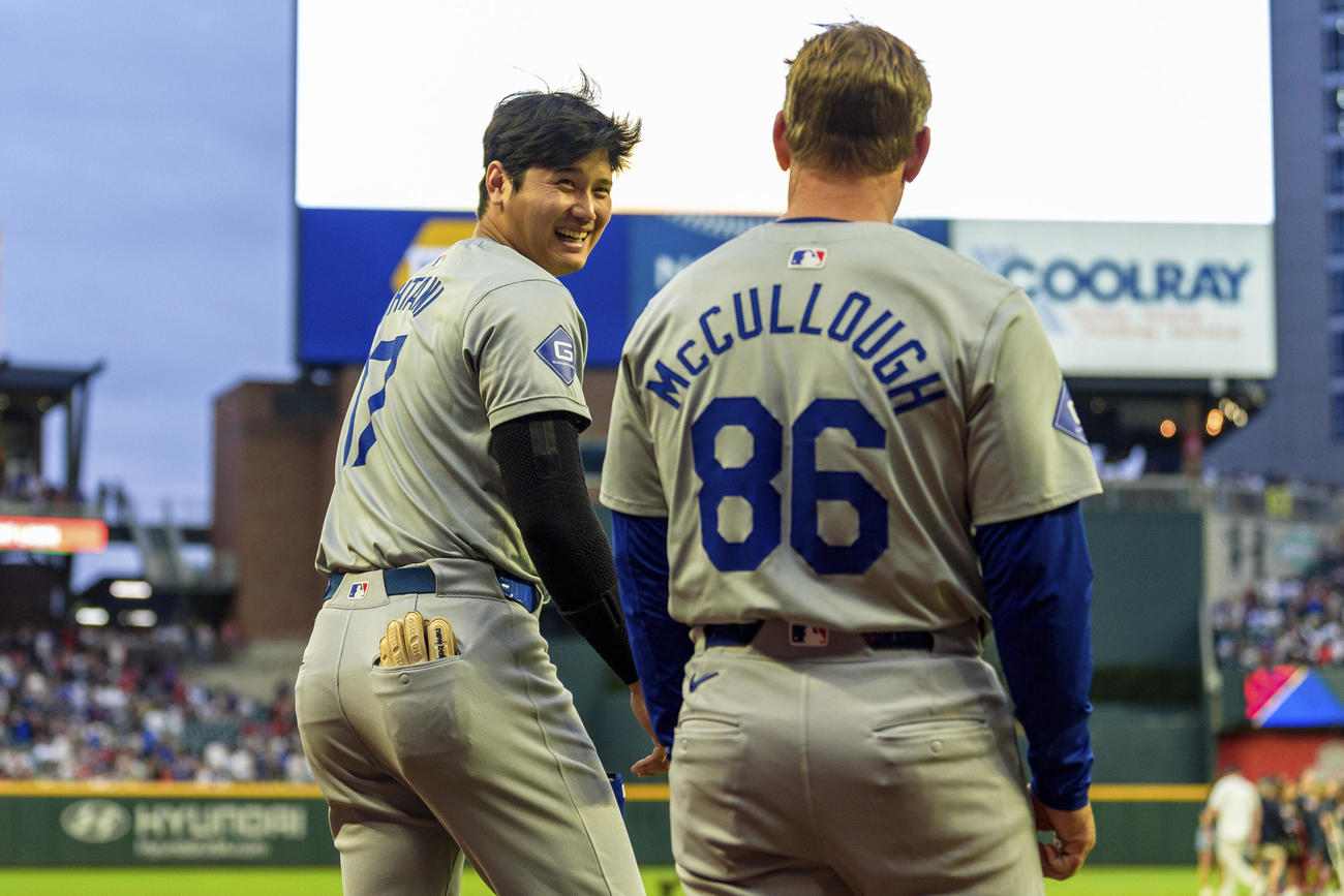 ドジャース大谷翔平（左）はブレーブス戦の国歌斉唱後にフィールドに出る前、一塁コーチのクレイトン・マカローと笑い合う（AP)