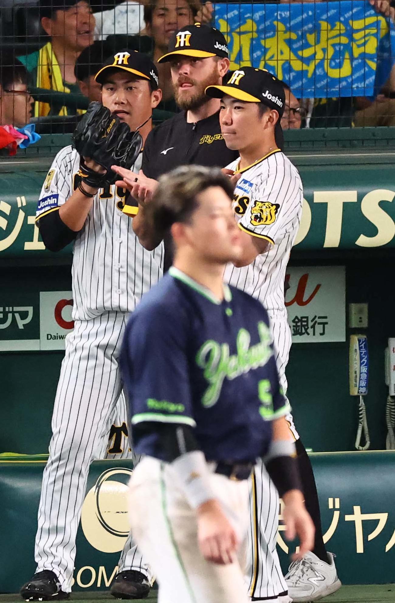 阪神対ヤクルト　8回表ヤクルト2死一、二塁、村上（手前）を中飛に打ち取った桐敷（左）はベンチ前でナインを出迎える。中央はビーズリー、右は石井（撮影・上田博志）