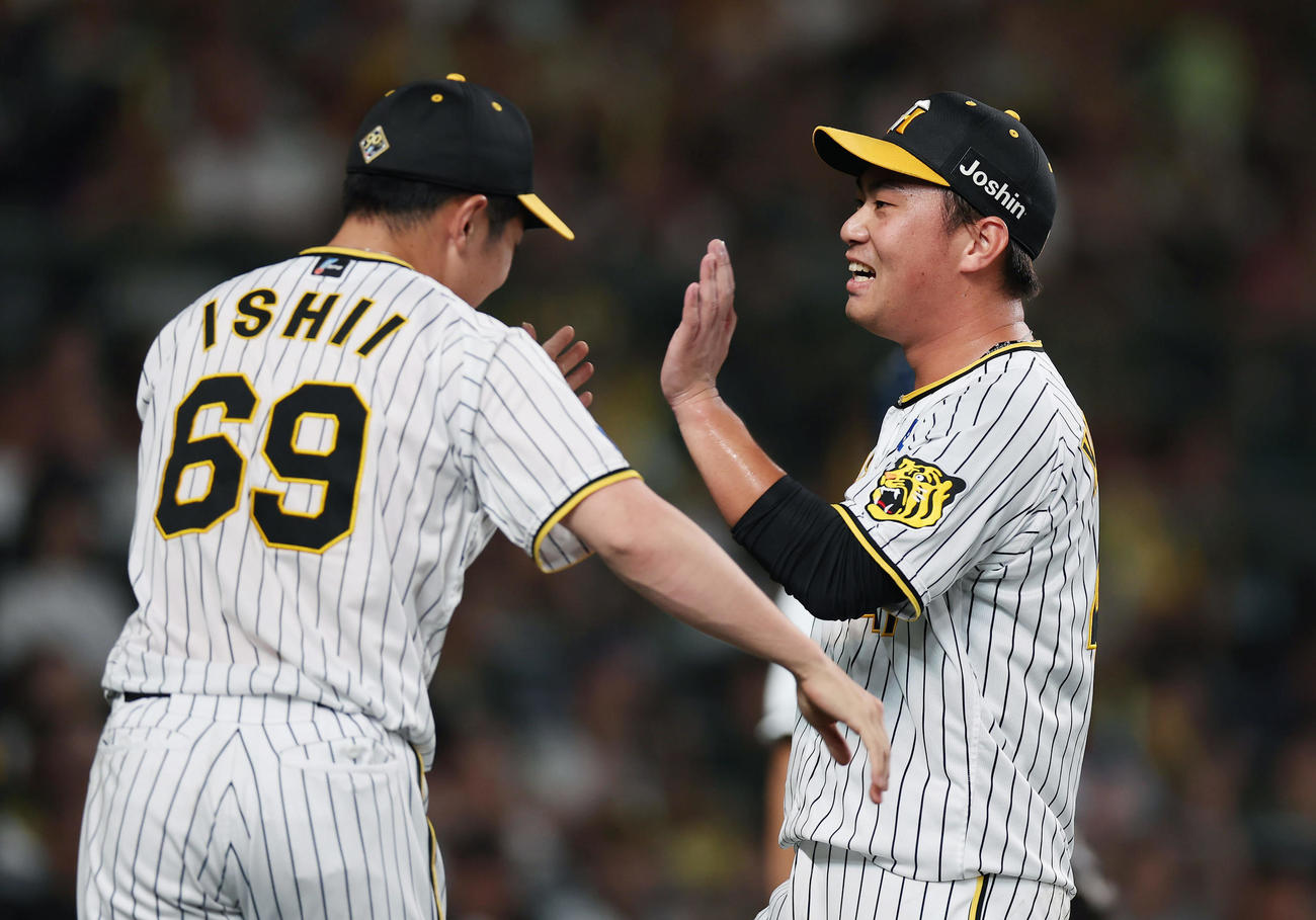 阪神対ヤクルト　8回表ヤクルト2死一、二塁、村上を中飛に仕留め、迎えた石井（左）と笑顔でタッチを交わす桐敷（撮影・前田充）