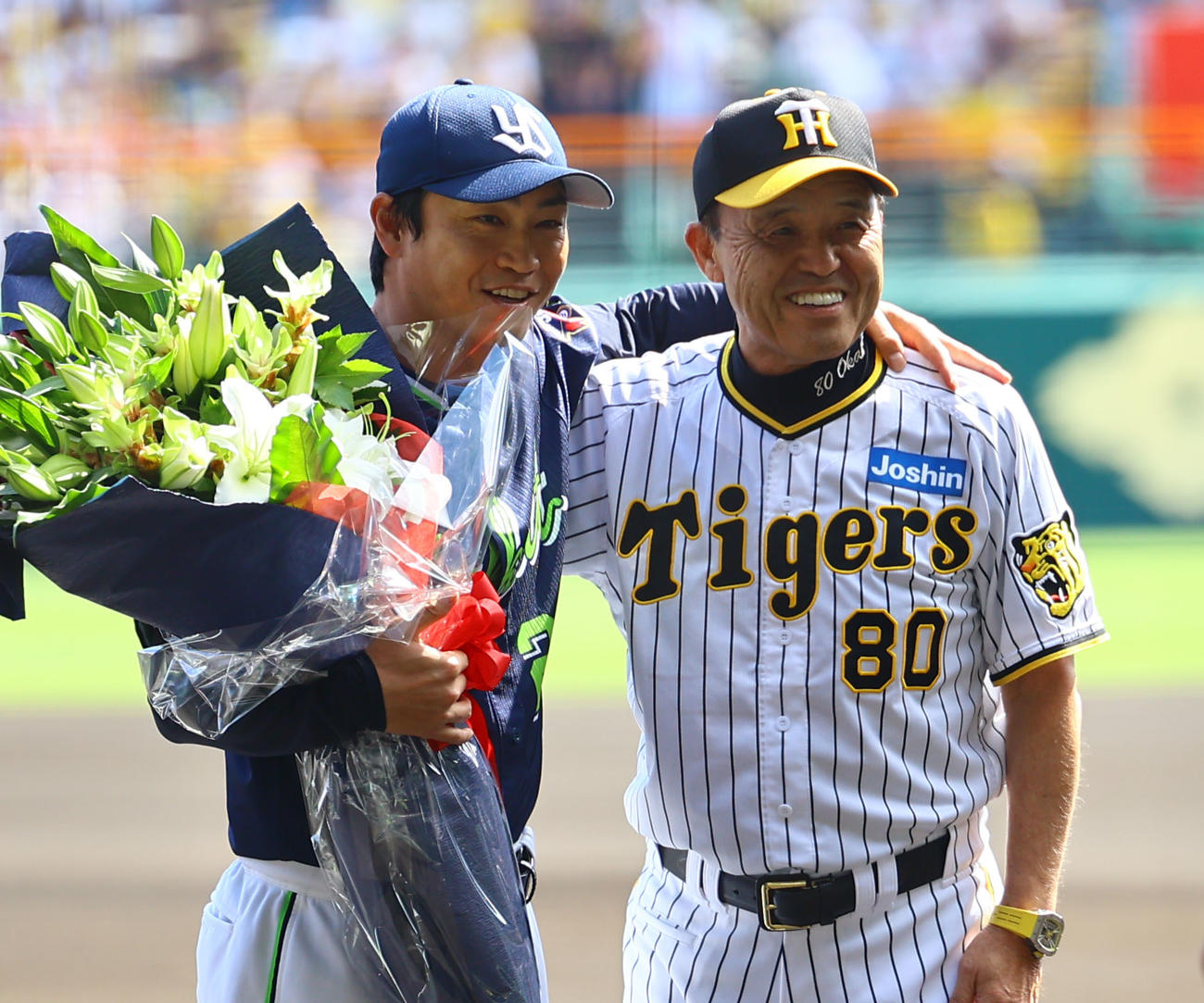 阪神対ヤクルト　阪神岡田監督（右）から花束を受け取り、笑顔で肩を組むヤクルト青木（撮影・藤尾明華）