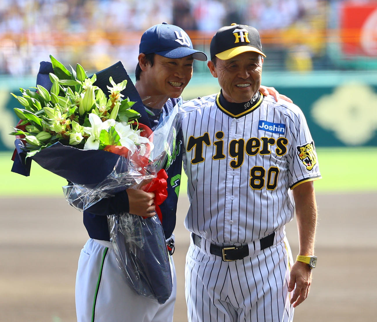 阪神対ヤクルト　阪神岡田監督（右）から花束を受け取り、笑顔で肩を組むヤクルト青木（撮影・藤尾明華）