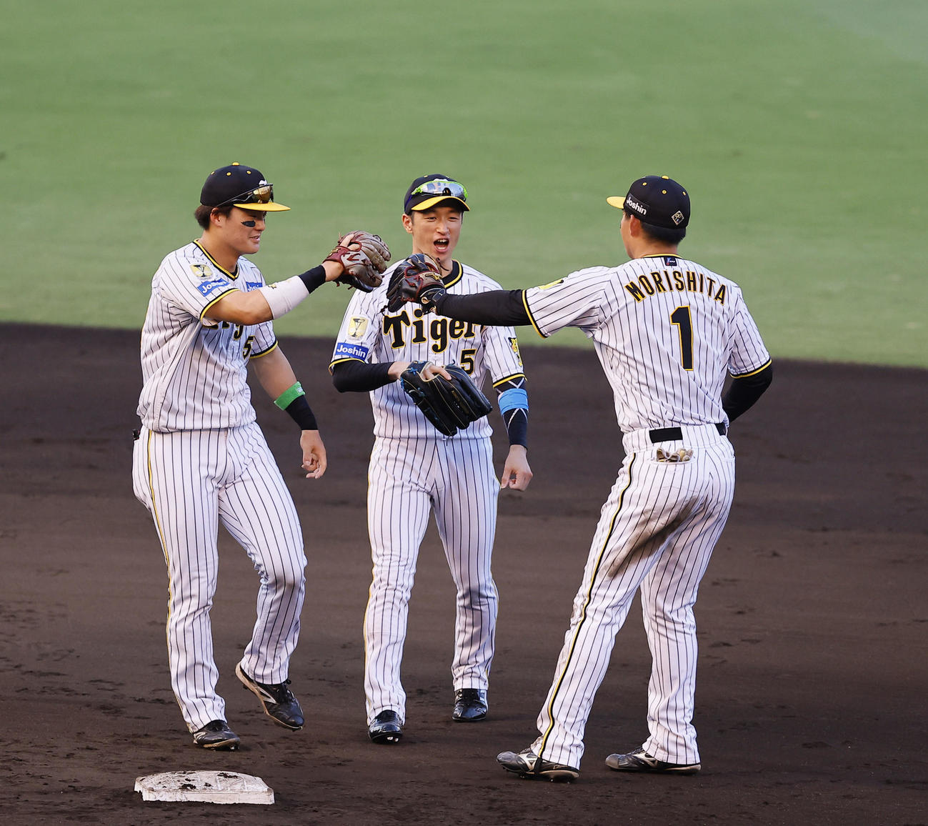 阪神対ヤクルト　勝利を飾りタッチを交わす左から阪神前川、近本、森下（撮影・藤尾明華）