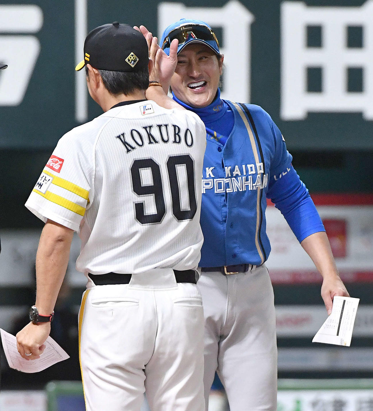 ソフトバンク対日本ハム　試合前のメンバー表交換で、ソフトバンク小久保監督（左）と笑顔でハイタッチする日本ハム新庄監督（撮影・岩下翔太）