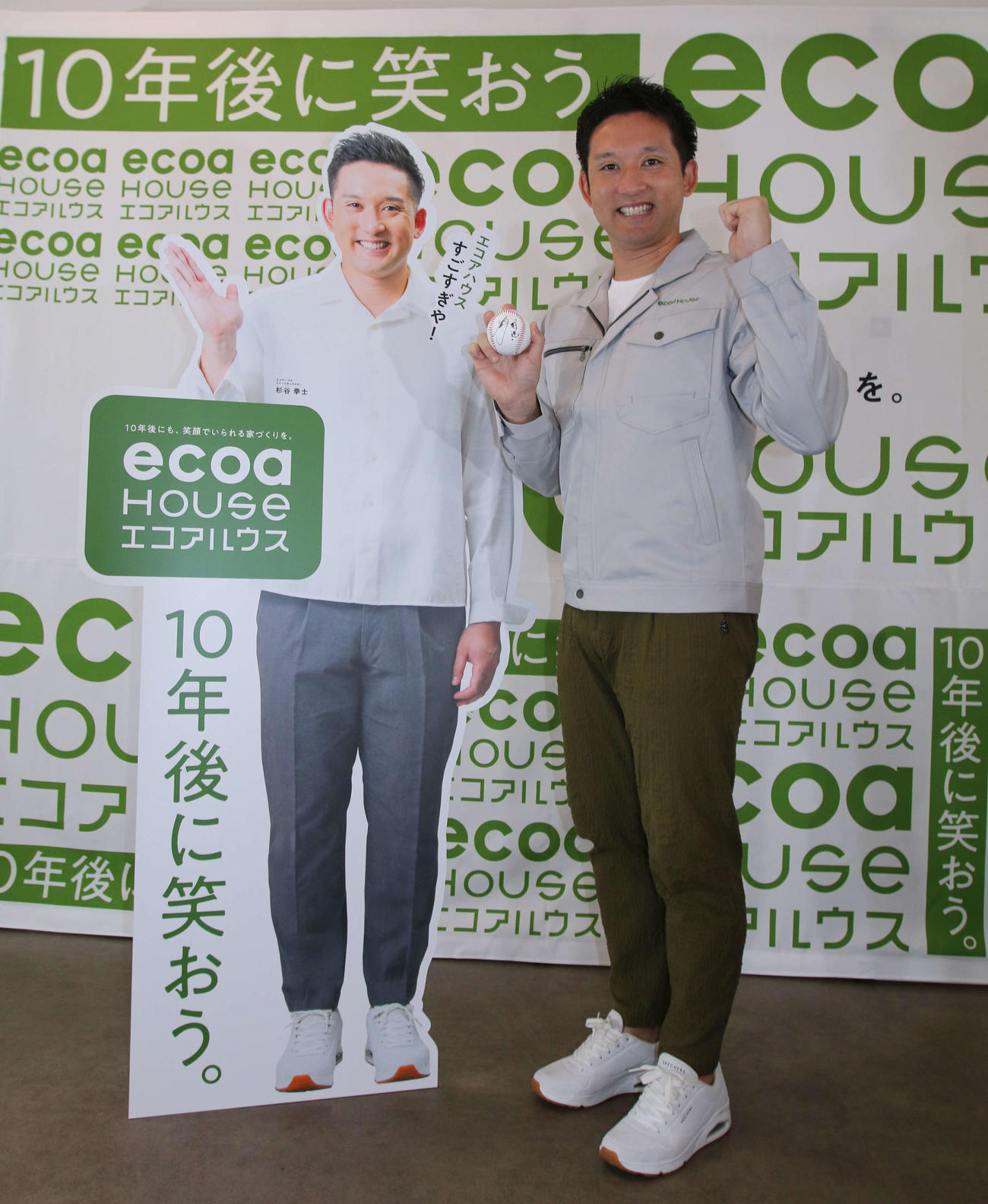 自身の看板とともにポーズを取る杉谷氏