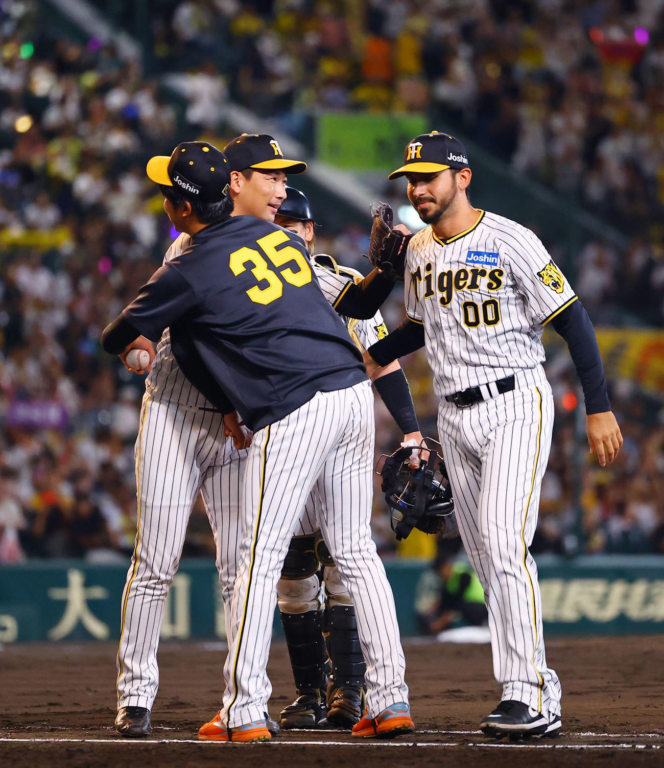 阪神対巨人　巨人に勝利し、才木と抱き合う阪神岩崎（左奥）。右はゲラ（撮影・藤尾明華）