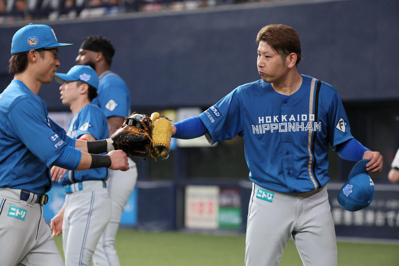 オリックス対日本ハム　4回裏を抑えた日本ハム先発の加藤（右）は江越とグラブタッチ（撮影・宮崎幸一）