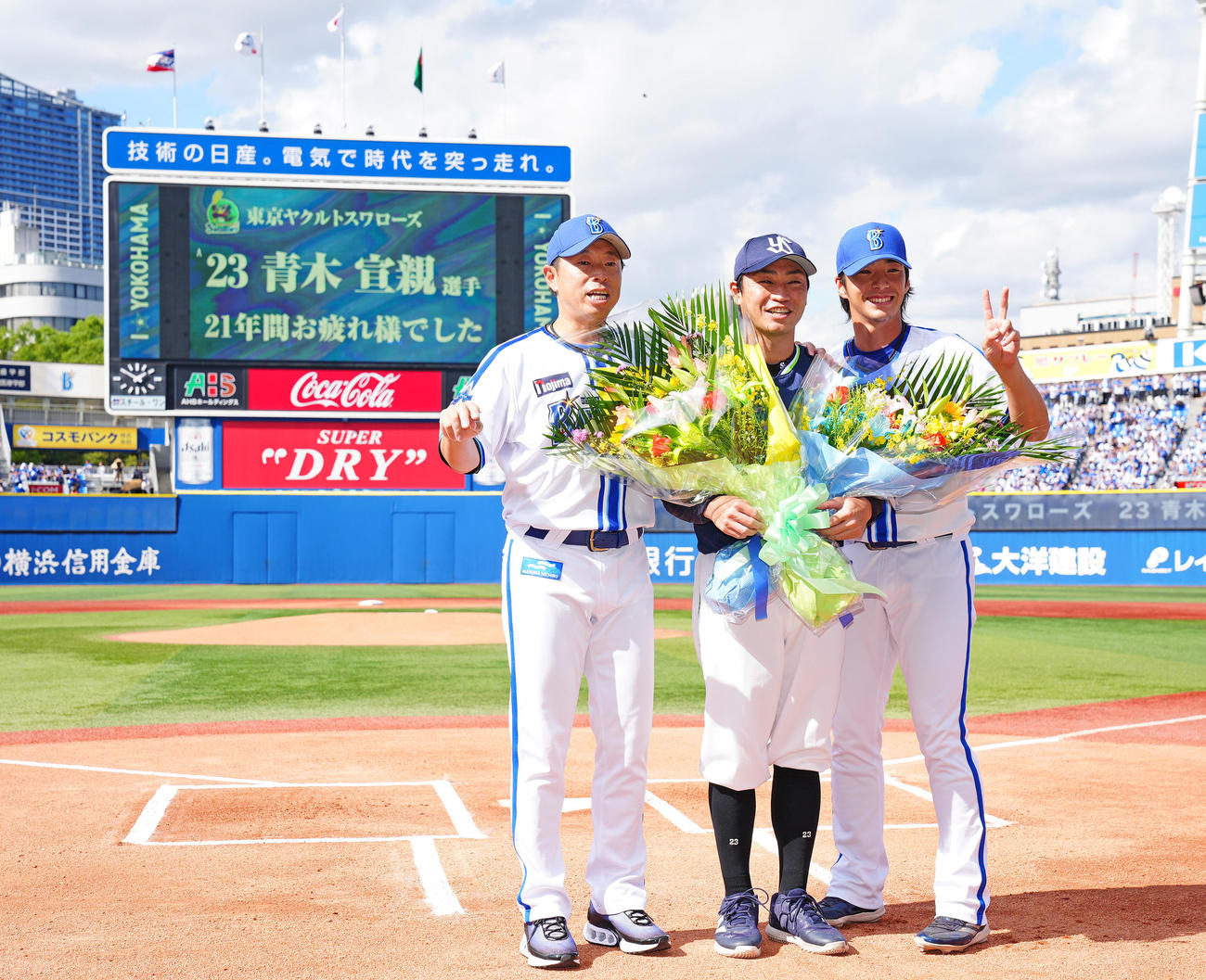 DeNA対ヤクルト　試合前、DeNA田中コーチ（左）、度会（右）から花束を受け取り写真に納まるヤクルト青木（撮影・垰建太）
