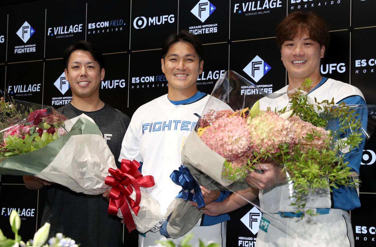 引退会見で北山サブマネージャー（左）と伏見（右）から花束を受け取り笑顔の日本ハム鍵谷（撮影・黒川智章）