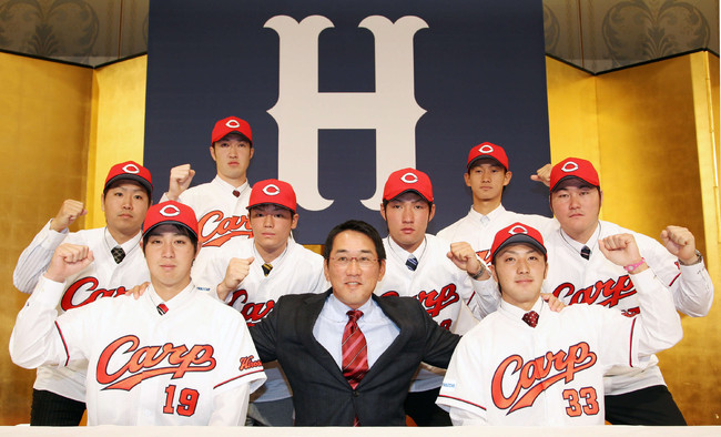 野村謙二郎監督を中心にポーズを取る広島の新人選手。前列左は野村祐輔、右は菊池涼介、中列左から富永一、戸田隆矢、土生翔平、中村真崇、後列左から塚田晃平、三家和真＝2011年12月13日