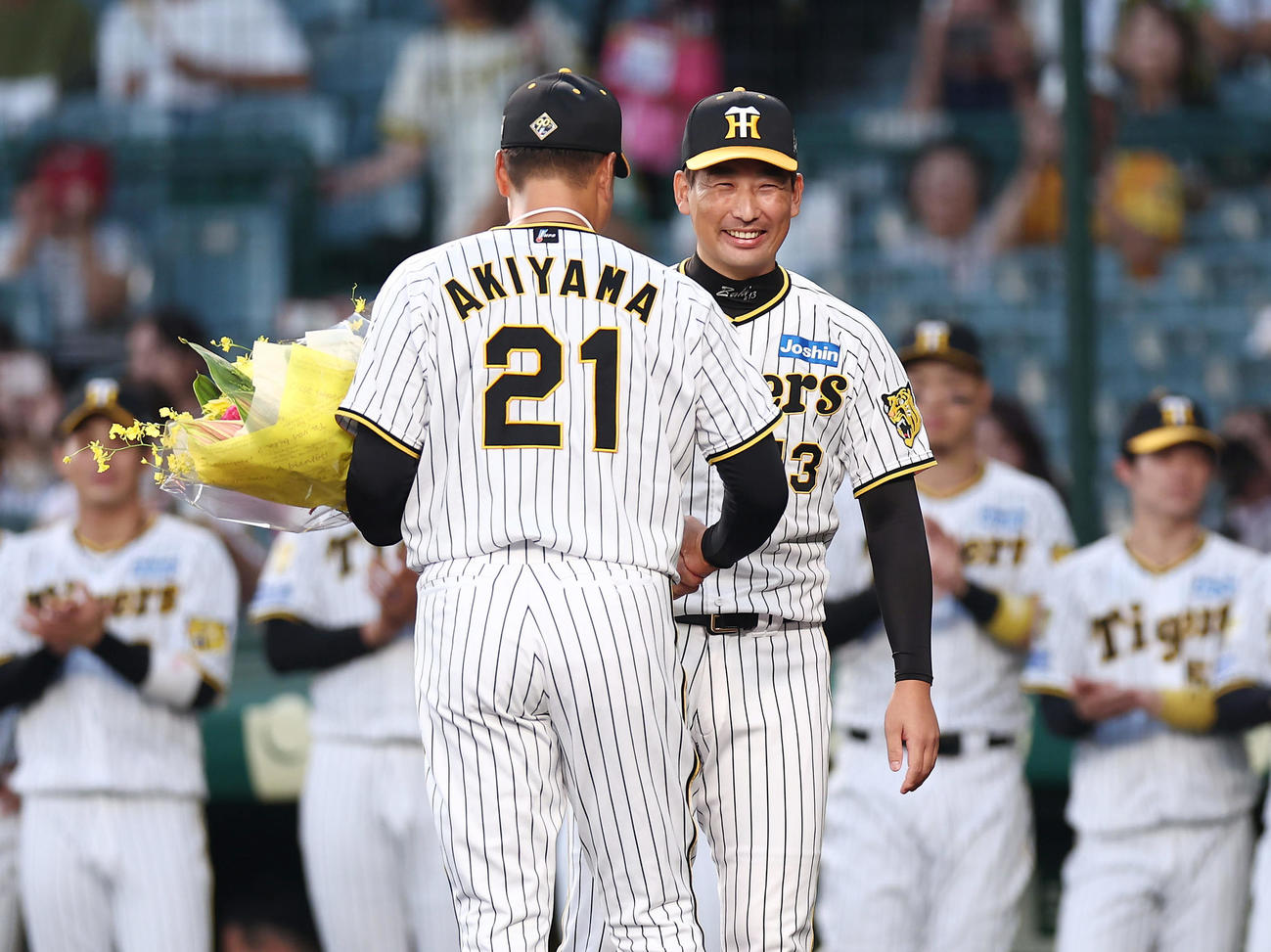 阪神対DeNA　ファイナルピッチセレモニーで阪神秋山（手前）に笑顔で花束を渡す岩崎（撮影・前田充）