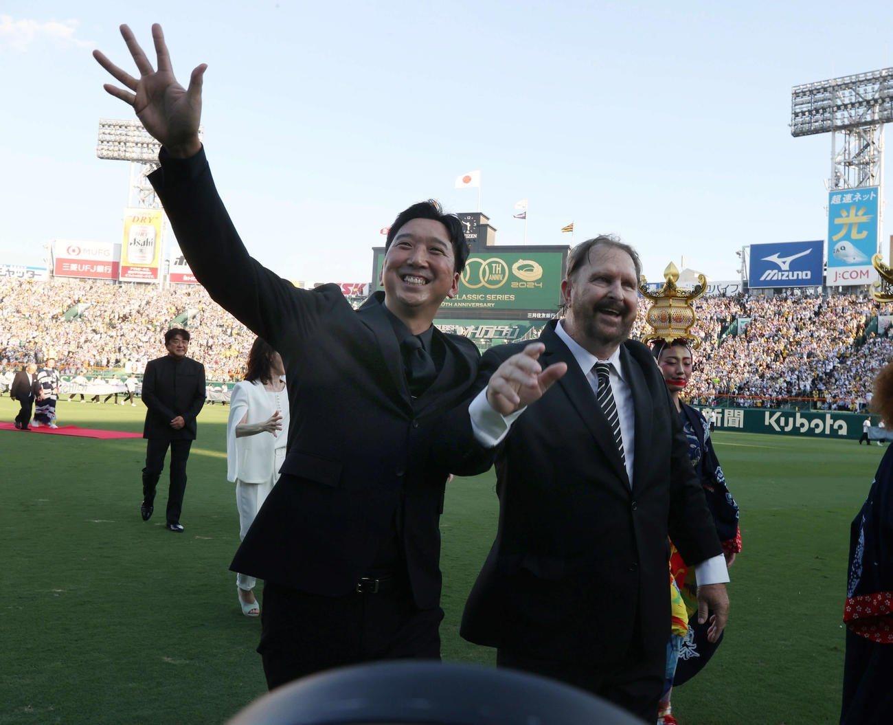 24年8月1日　阪神対巨人　100周年セレモニーに出席しファンに手を振る阪神OBの藤川球児氏（左）とランディ・バース氏