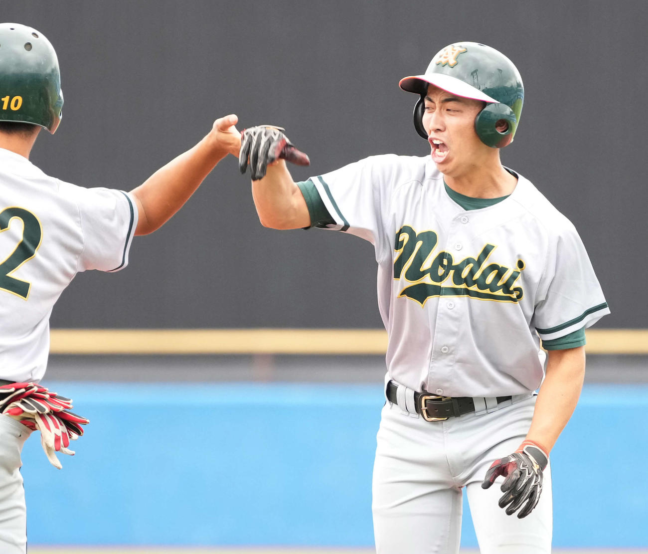 東農大対青学大　8回表東農大2死三塁、代打合志（右）は三前に勝ち越しの適時内野安打を放ち一塁コーチとハイタッチ（撮影・小沢裕）