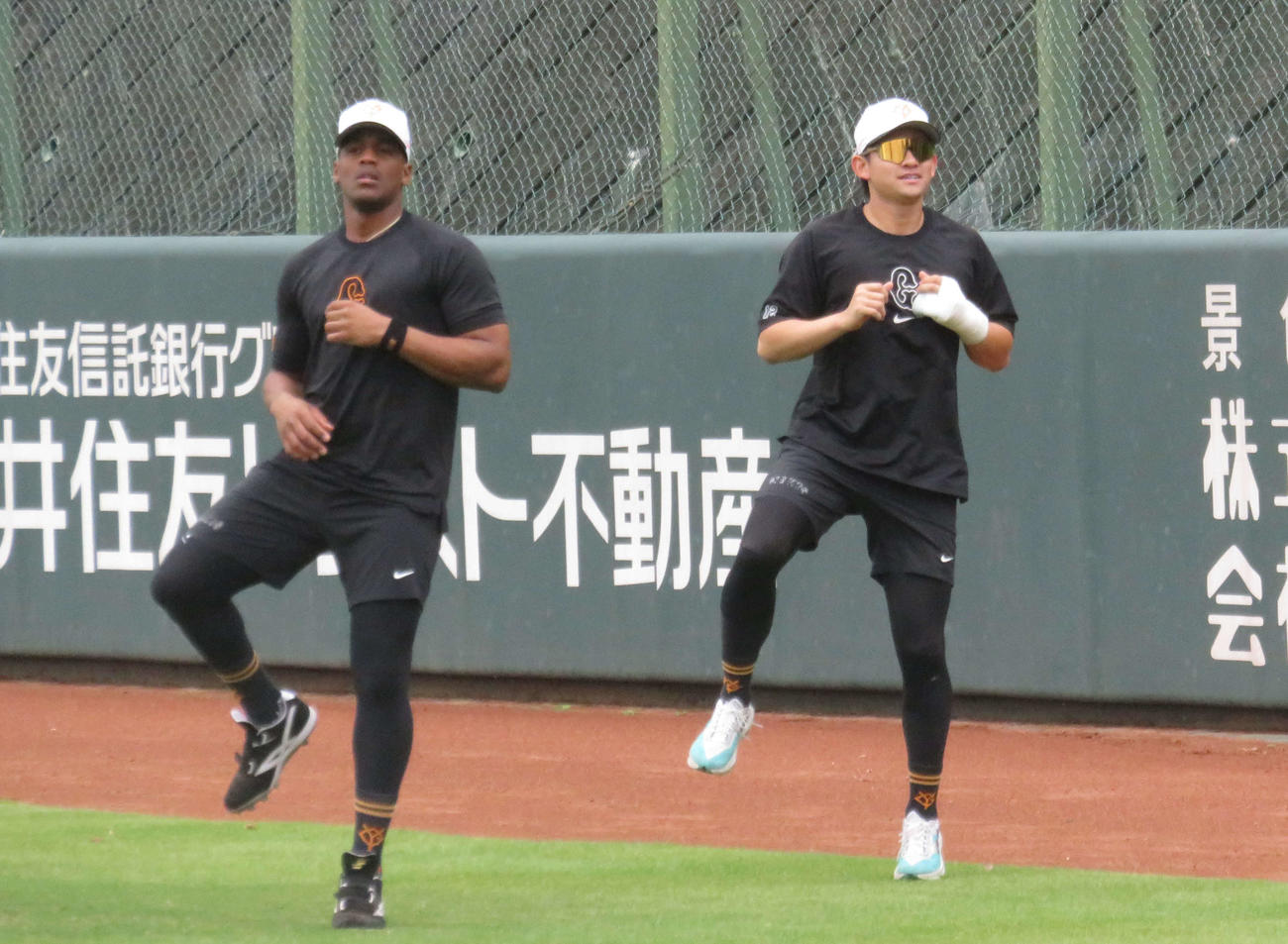 故障班でウオーミングアップを行う巨人ヘルナンデス外野手（左）と萩尾