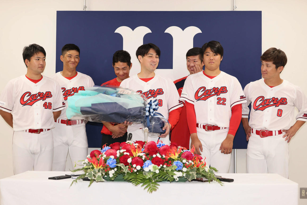 引退会見後、広陵OBと記念写真におさまる広島野村祐輔（中央）。左から河野、中村奨、土生スコアラー、野村、白浜スコアラー、高、上本（撮影・加藤孝規）