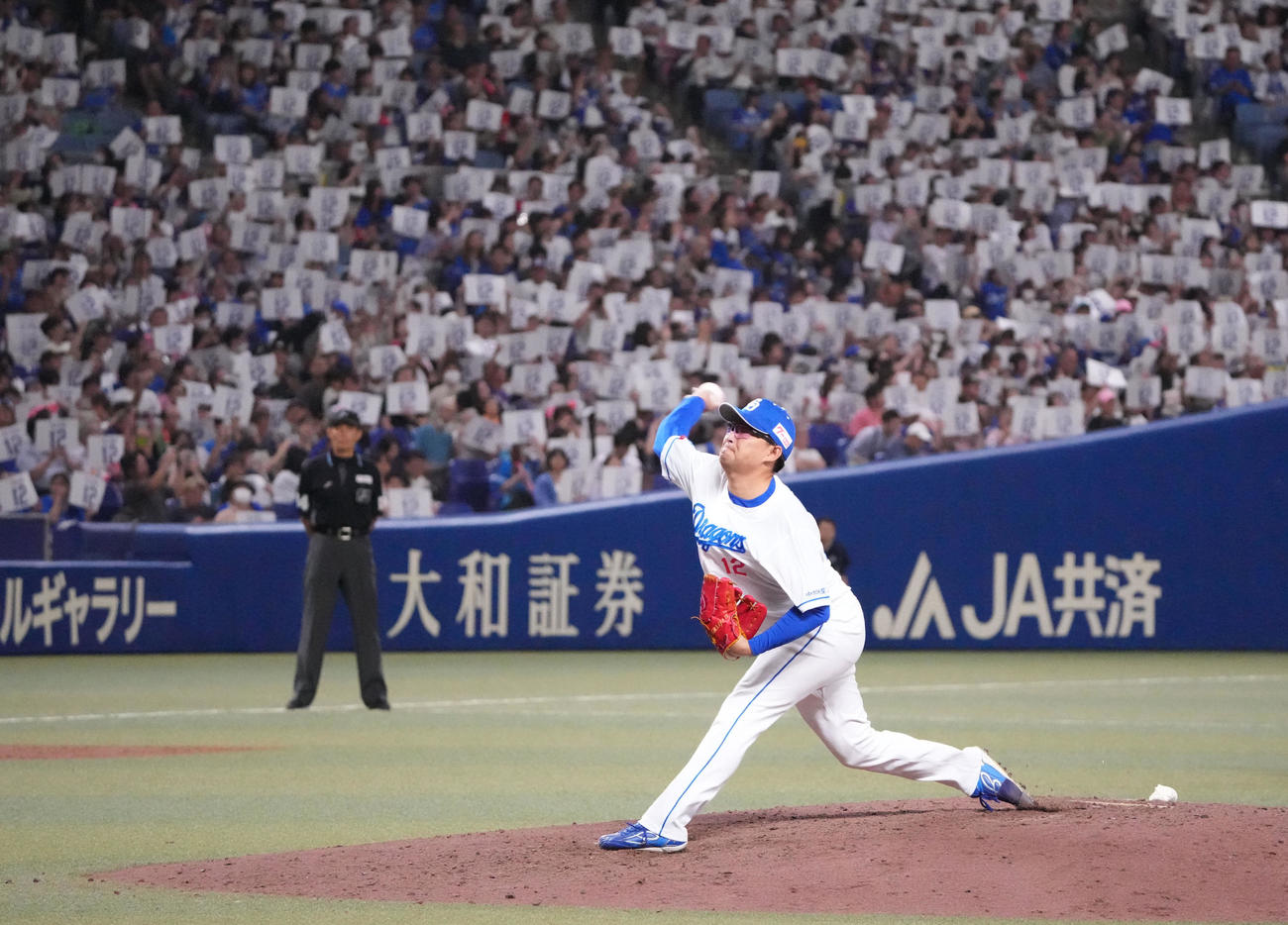 中日対DeNA 7回表DeNA1死、記念プラカードを掲げる観客の前で投球練習をする田島（撮影・森本幸一）