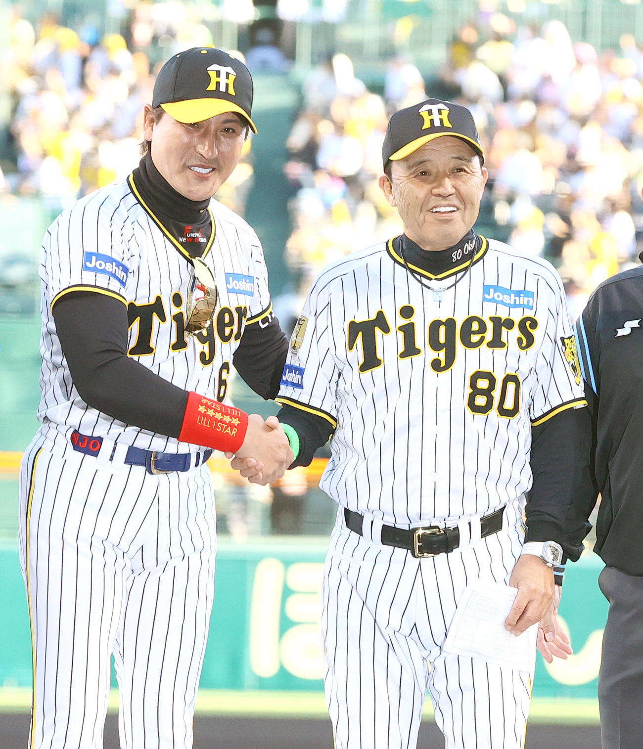 阪神対日本ハム　試合前のメンバー表確認で日本ハム新庄監督（左）は阪神のユニホームを着て岡田監督と握手をかわす（2024年5月29日撮影）
