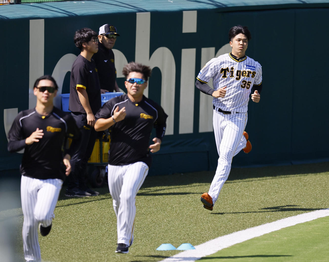 岡田監督（奥）が見つめる中、ランニングをする阪神才木（右端）（撮影・藤尾明華）