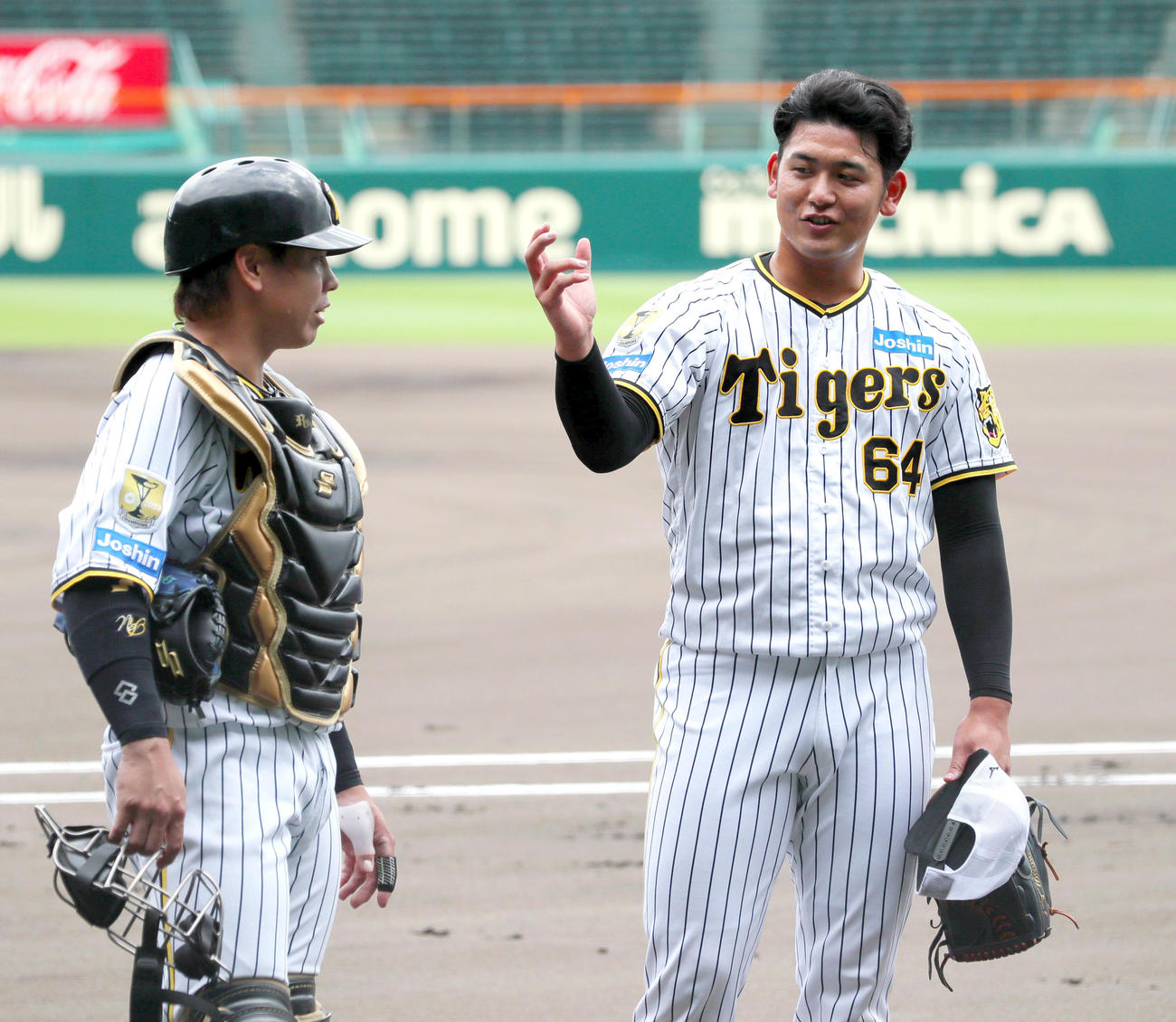 シート打撃で投球を終え捕手梅野（左）と話す阪神岡留（撮影・上山淳一）