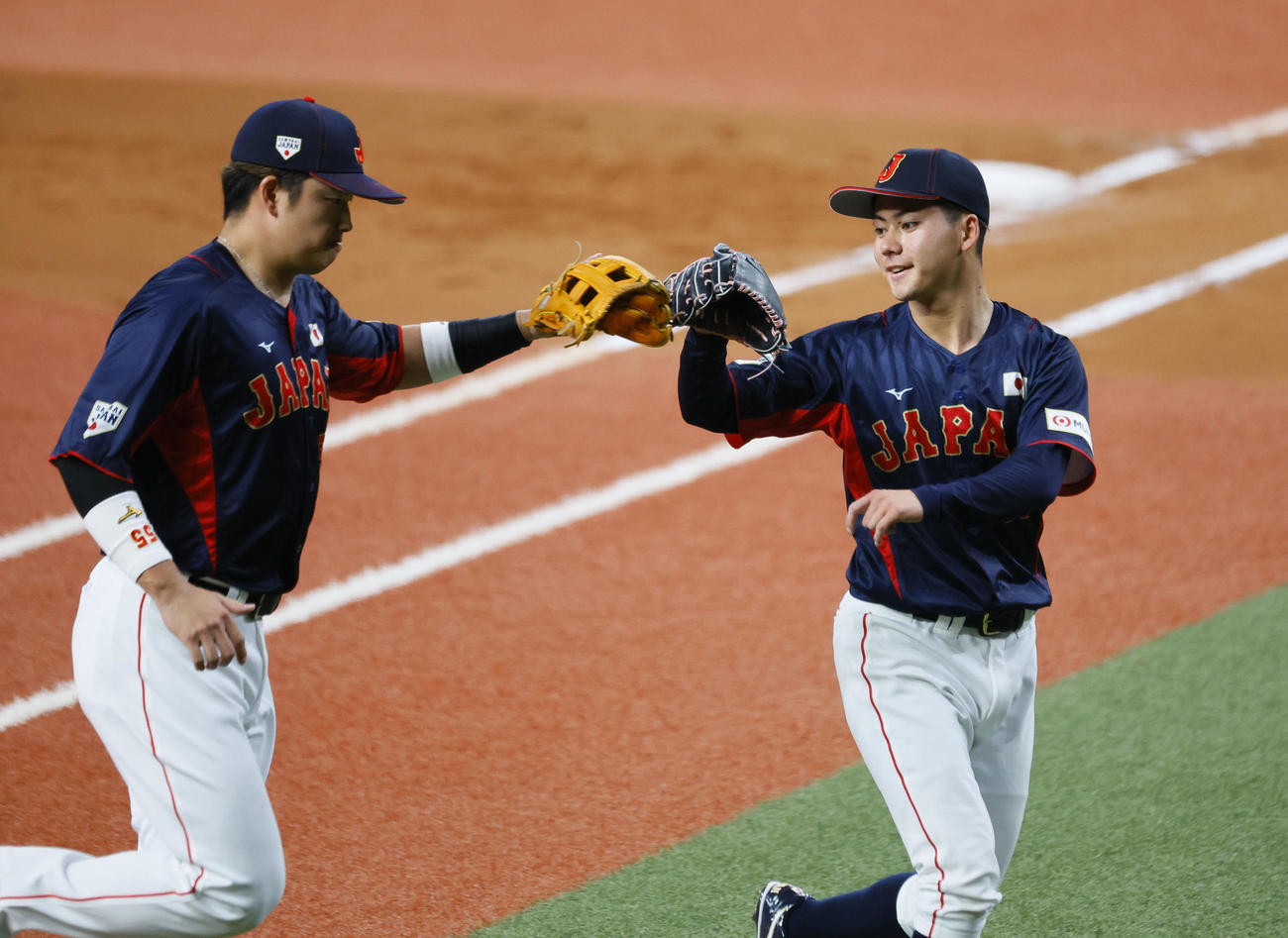 欧州対日本　1回を3者凡退に打ち取り、村上宗隆（左）とタッチを交わす日本金丸夢斗（撮影・藤尾明華）＝2024年3月7日、京セラドーム