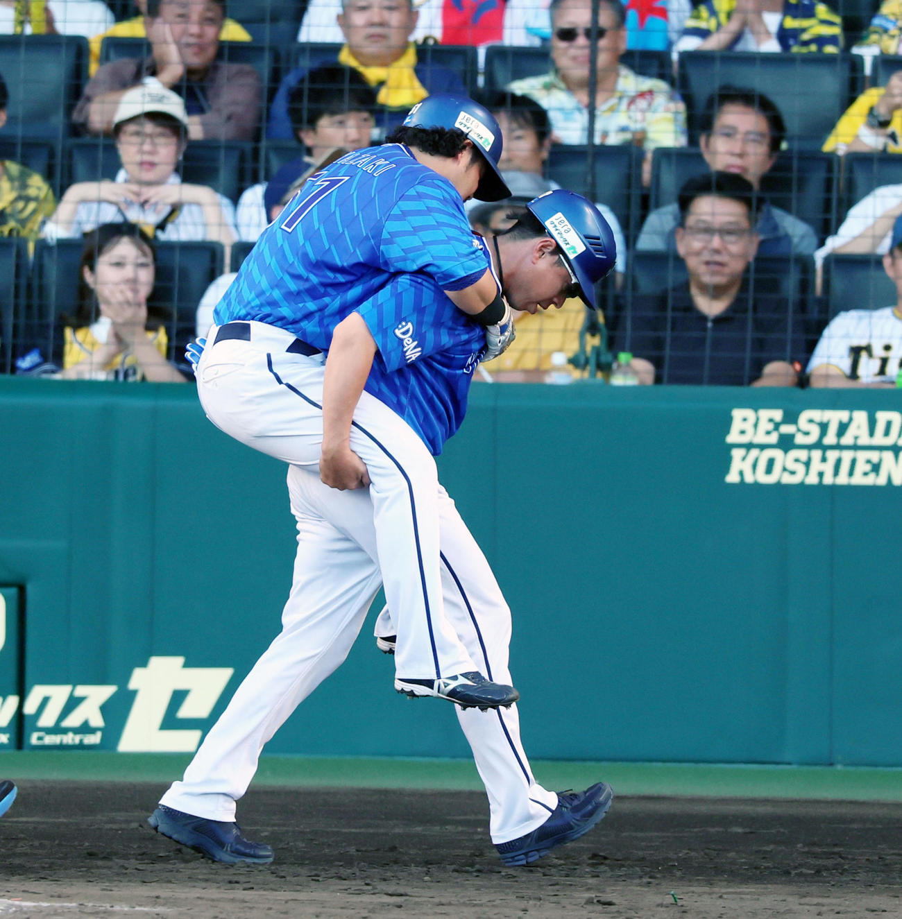 阪神対DeNA 7回表DeNA1死、宮崎は三ゴロを打ち負傷交代となり田中コーチがおんぶしてベンチへ引き揚げる（撮影・加藤哉）