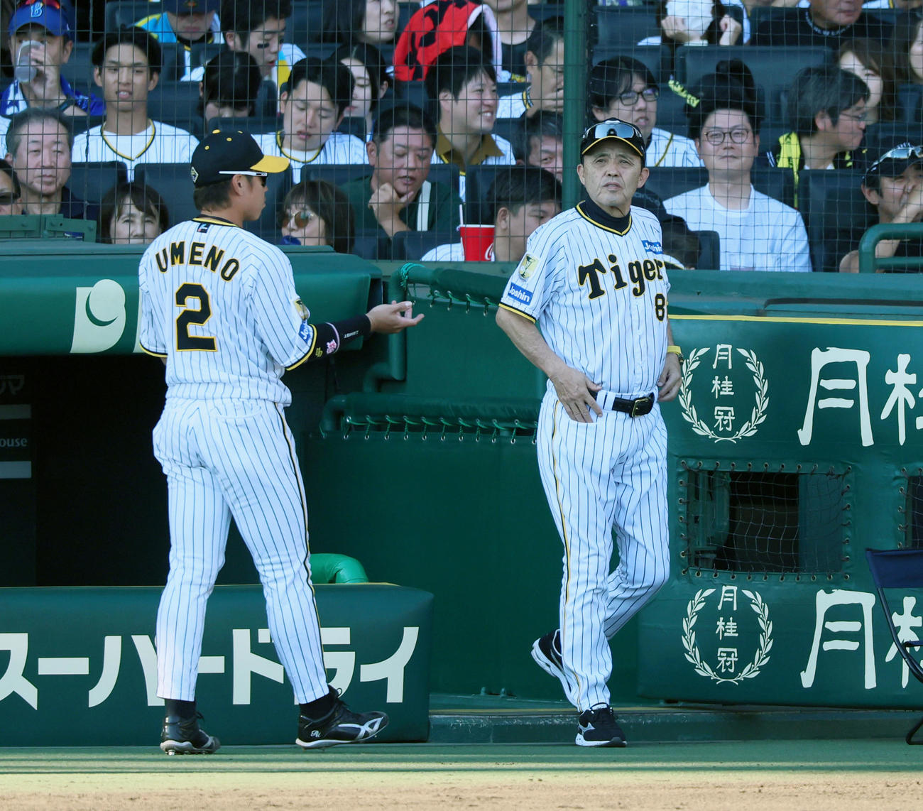 阪神対DeNA 5回裏を終え選手交代を告げる岡田監督。左は梅野（撮影・加藤哉）
