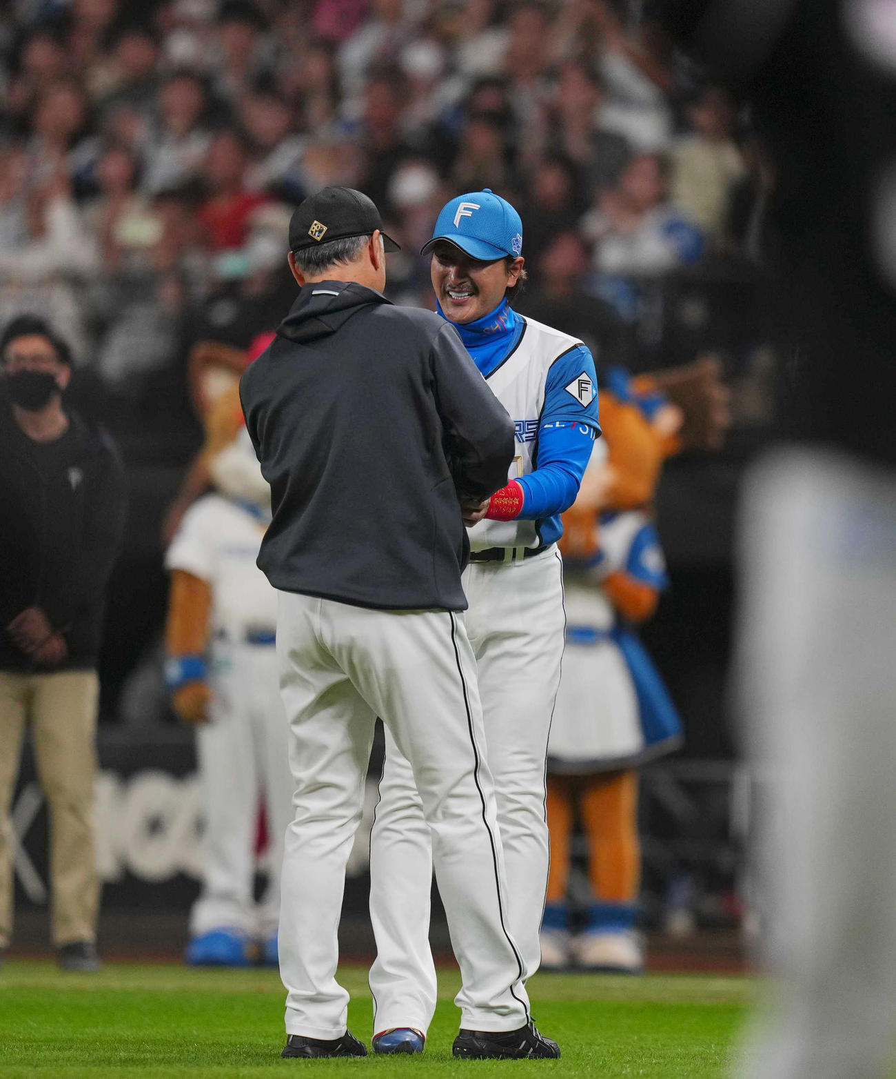 日本ハム対ロッテ　CSファイナル進出を決め、ロッテ吉井監督（手前）と健闘をたたえ合う日本ハム新庄監督（撮影・狩俣裕三）