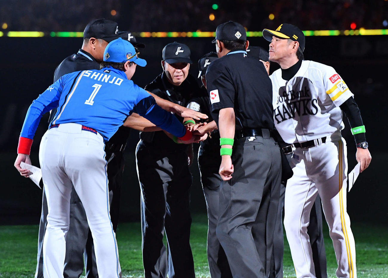 ソフトバンク対日本ハム　試合前、メンバー表を交換して審判団と円陣を組む日本ハム新庄監督（左）とソフトバンク小久保監督（撮影・岩下翔太）
