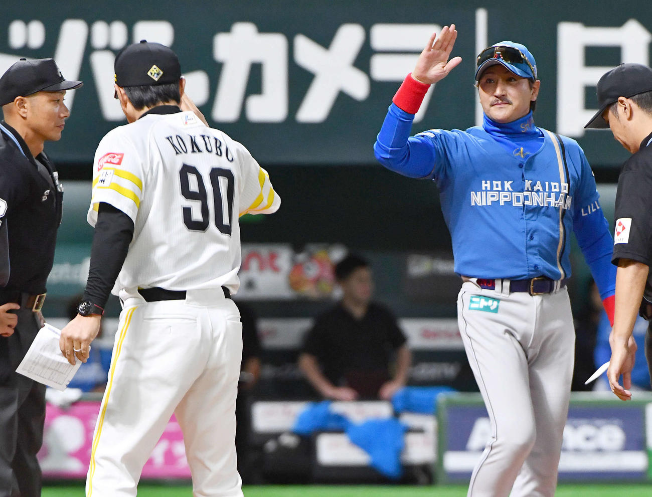 ソフトバンク対日本ハム　試合前、ソフトバンク小久保監督（左）とメンバー表を交換して手を振る日本ハム新庄監督（撮影・岩下翔太）