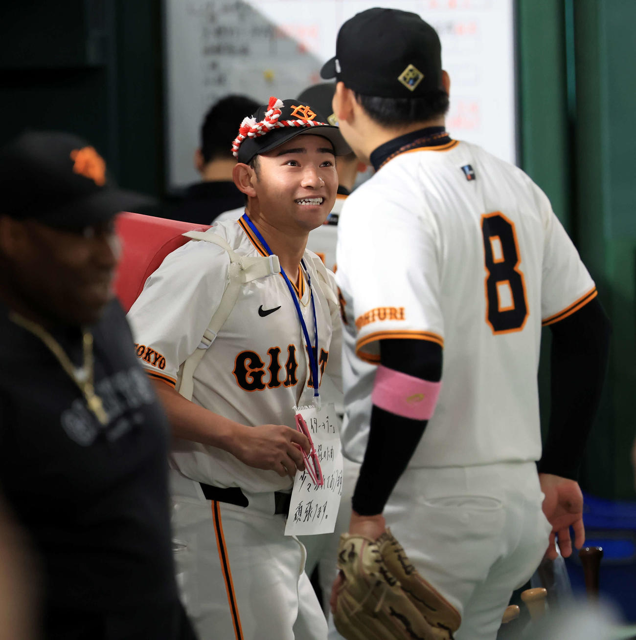 巨人対DeNA　巨人の試合前円陣の声出しに登場した赤いカバン？を背負った萩尾のボードには「ナイター→デー日程のため少々疲れております」と書かれていた（撮影・浅見桂子）