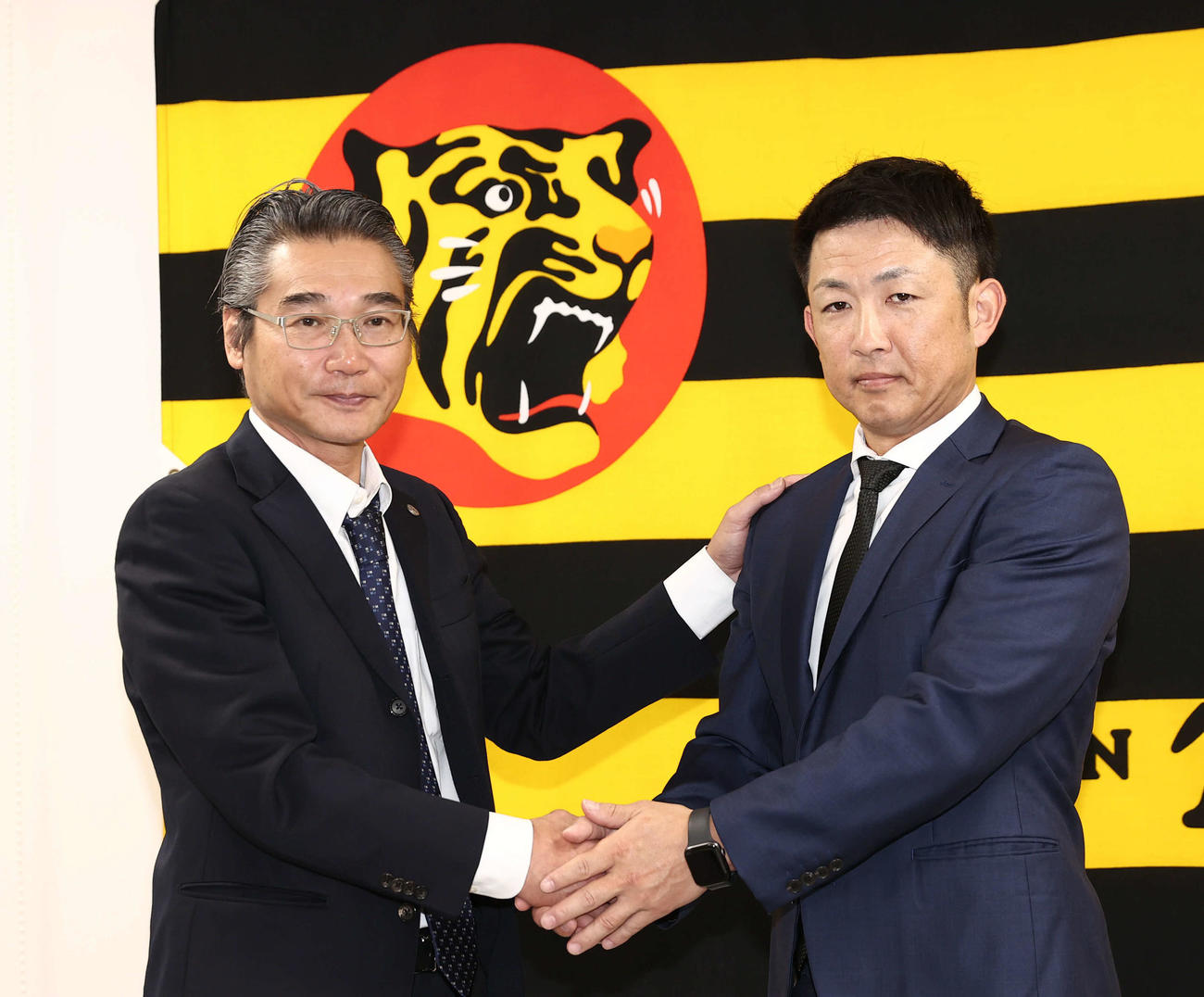 阪神2軍打撃コーチに就任した梵氏（右）は嶌村球団本部長と握手をかわす