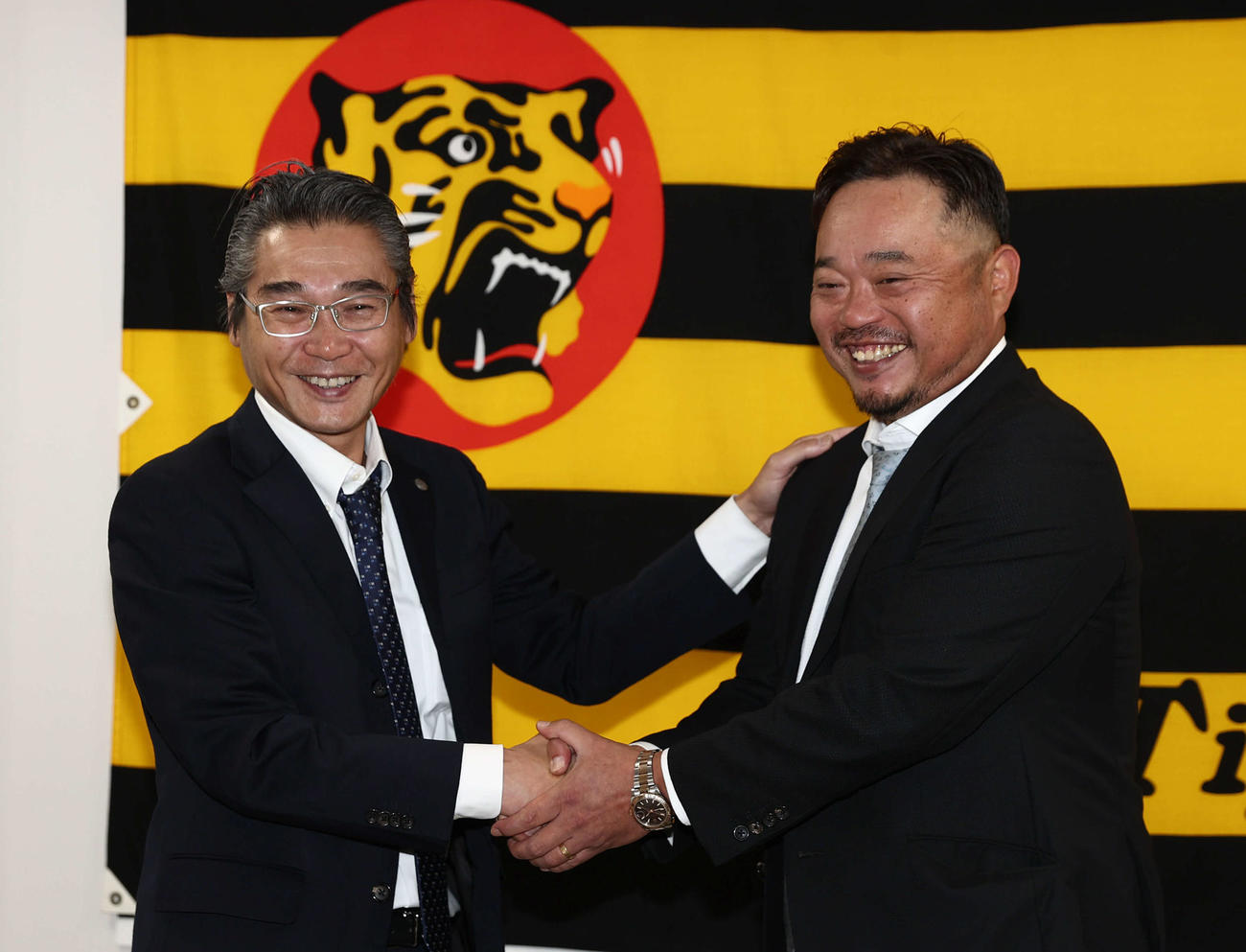 1軍打撃チーフコーチに就任した小谷野氏（右）は嶌村球団本部長と笑顔で握手を交わす（西宮市内）（撮影・西尾就之）