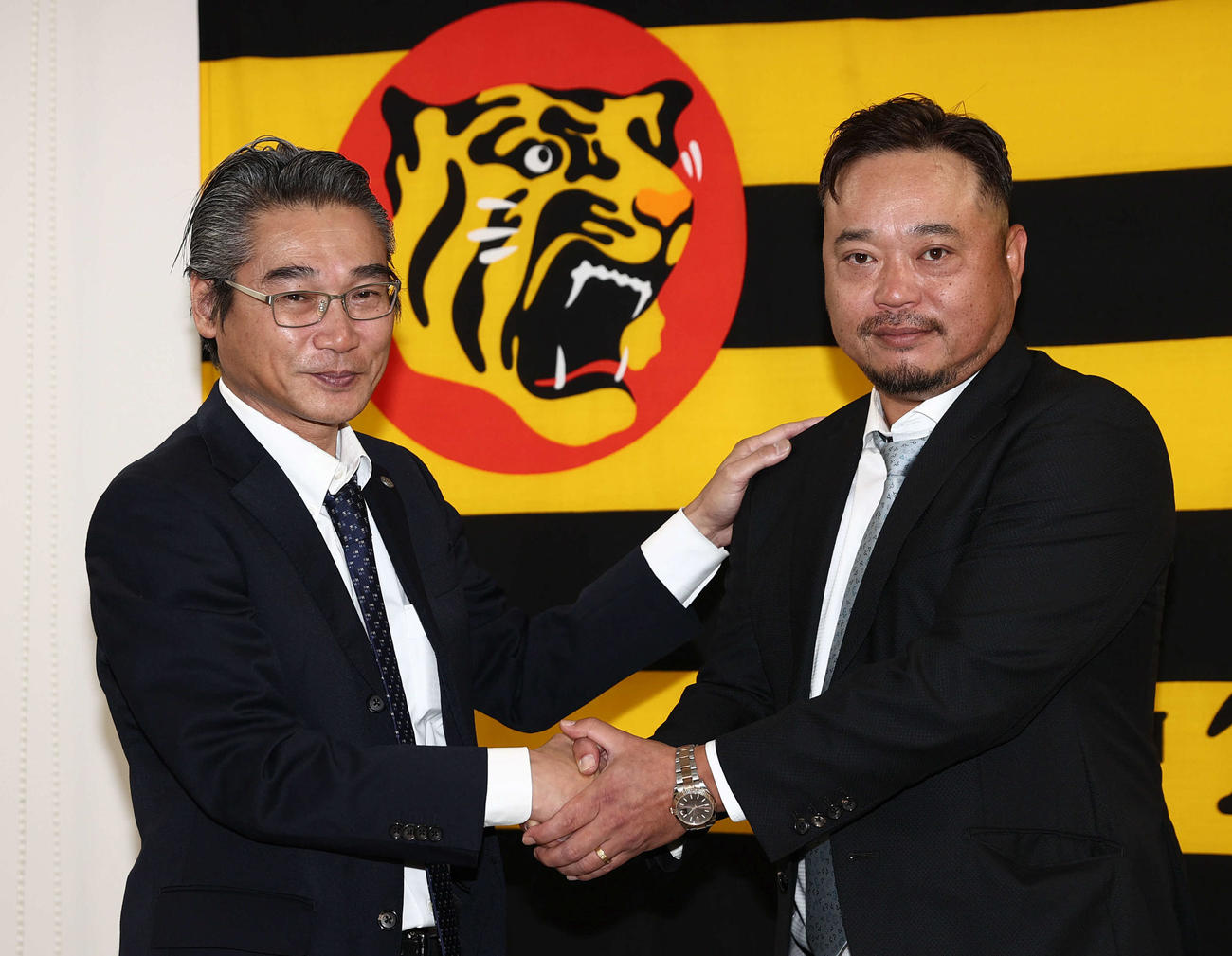 1軍打撃チーフコーチに就任した小谷野氏（右）は嶌村球団本部長と握手を交わす（西宮市内）（撮影・西尾就之）