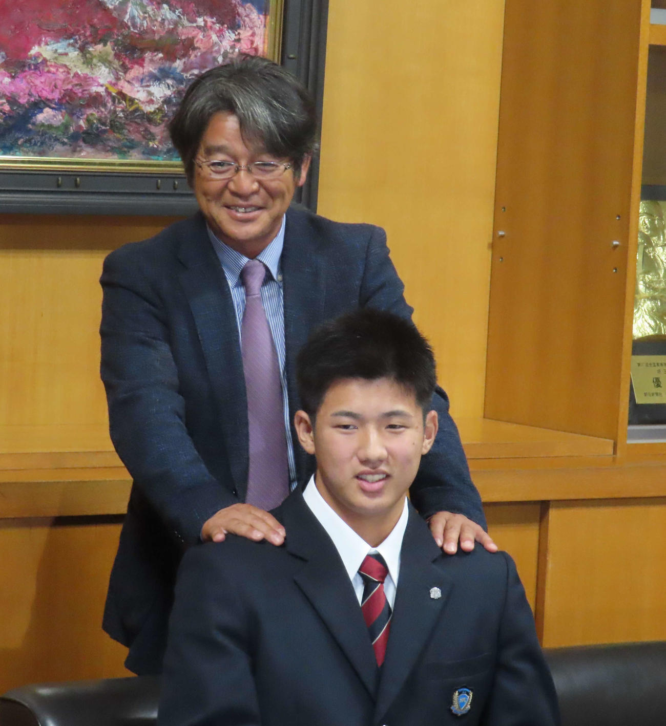 巨人からドラフト1位指名を受け花咲徳栄・岩井監督（後ろ）と笑顔で写真に納まる石塚（撮影・水谷京裕）