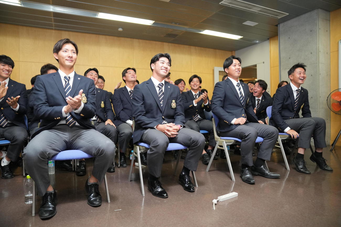 DeNAから指名を受け笑顔を見せる法大・篠木（左から2人目）（撮影・垰建太）