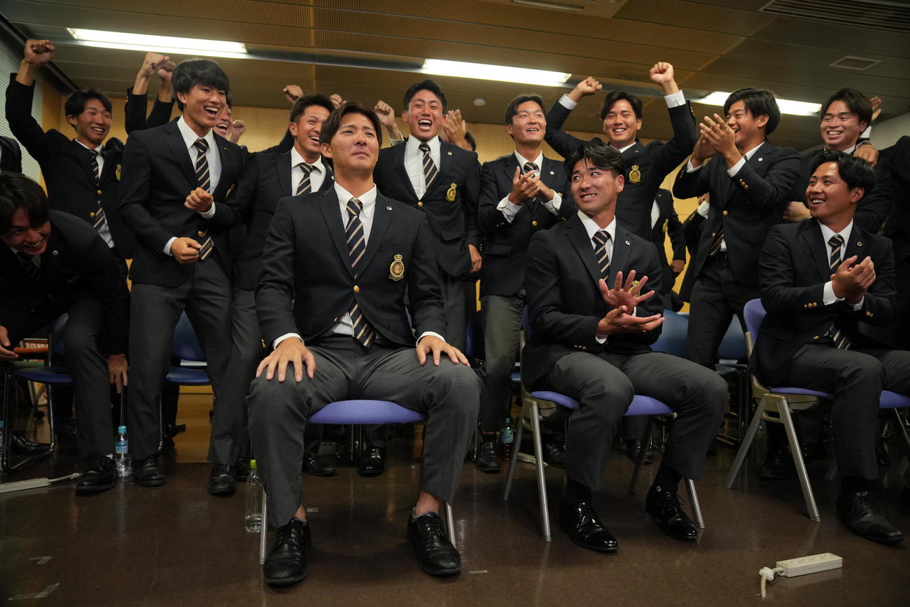 日本ハムから指名を受けほっとした表情を見せる法大・山城（手前左）。右は篠木（撮影・垰建太）