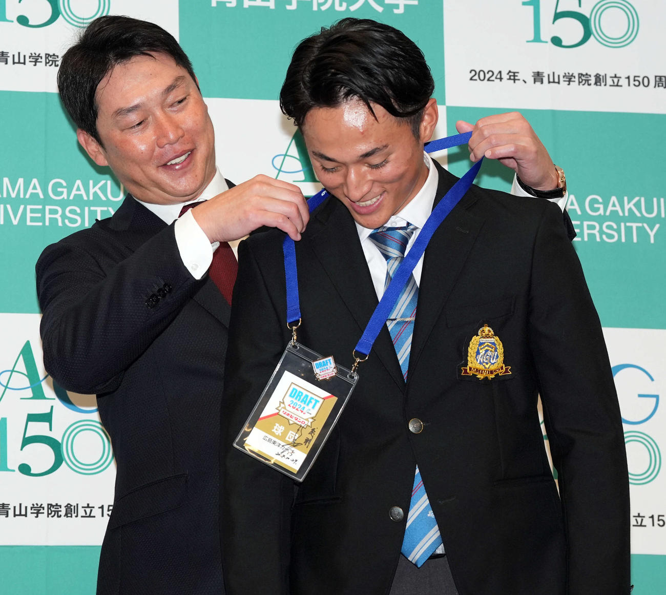 広島からドラフト1位の指名を受けた青学大・佐々木（右）は新井監督からドラフト会議のパスをかけてもらう（撮影・たえ見朱実）